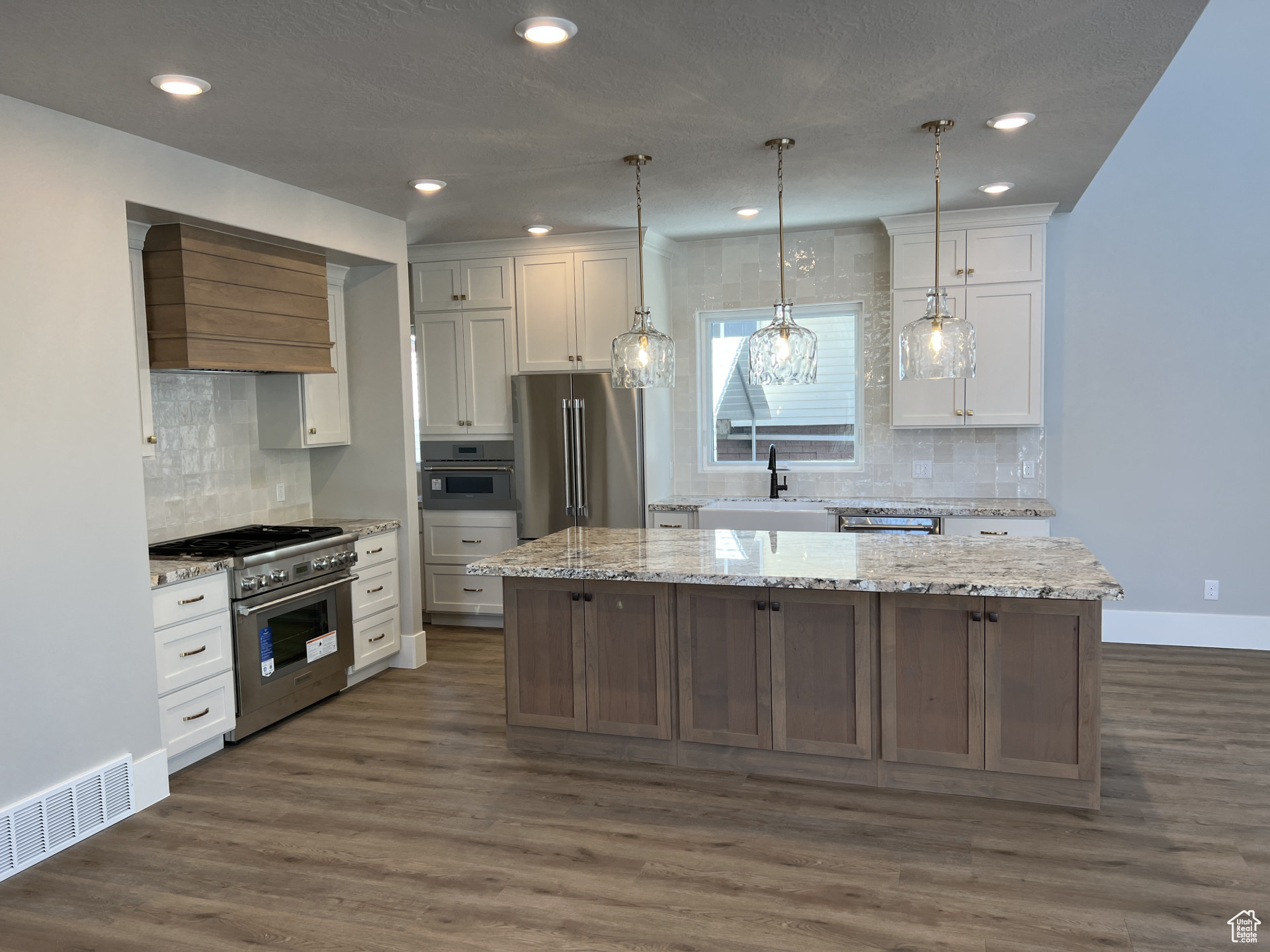 Kitchen with custom exhaust hood, white cabinetry, a center island, high quality appliances, and dark hardwood / wood-style floors