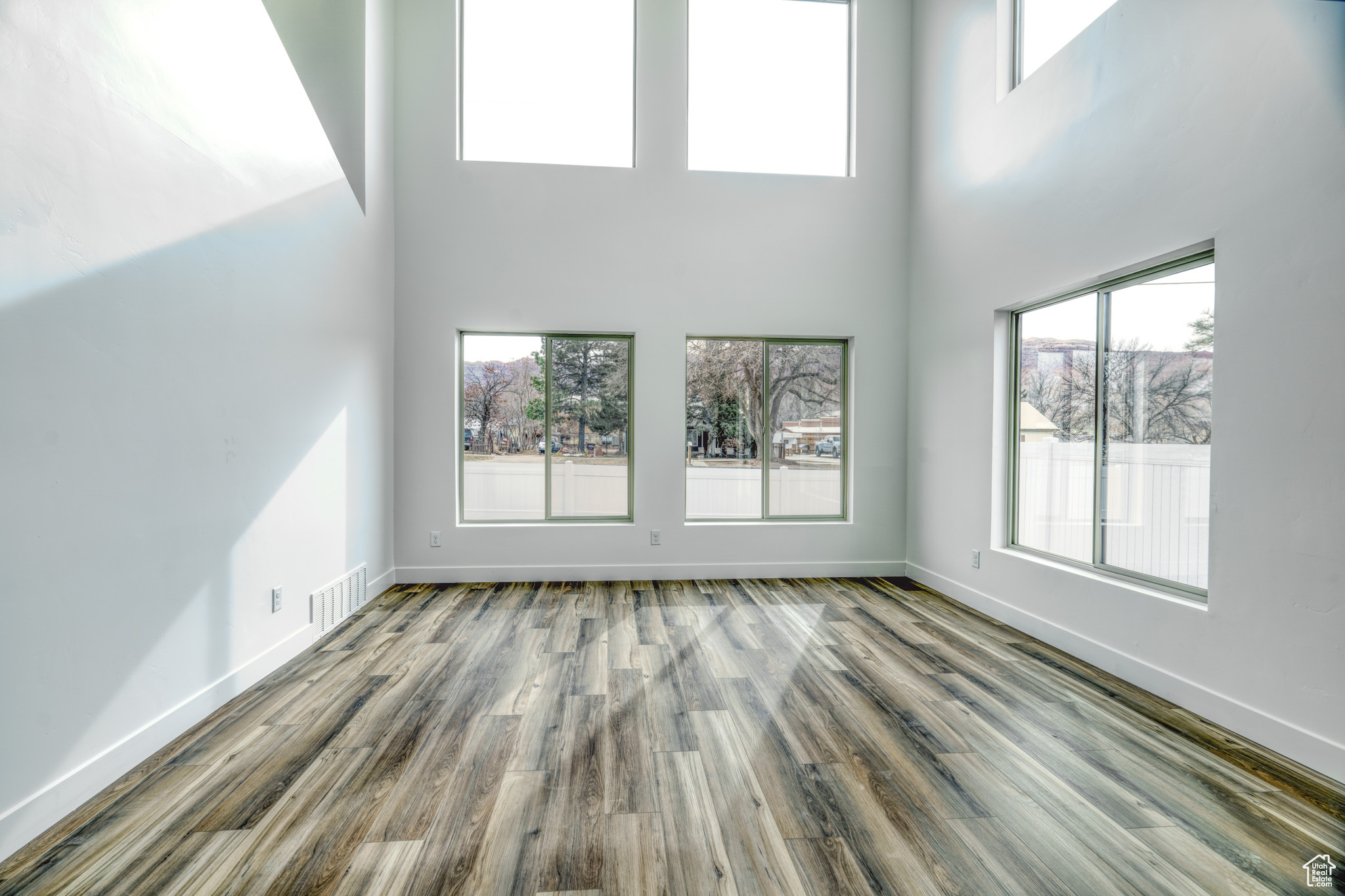 Unfurnished living room with hardwood / wood-style flooring, plenty of natural light, and a high ceiling
