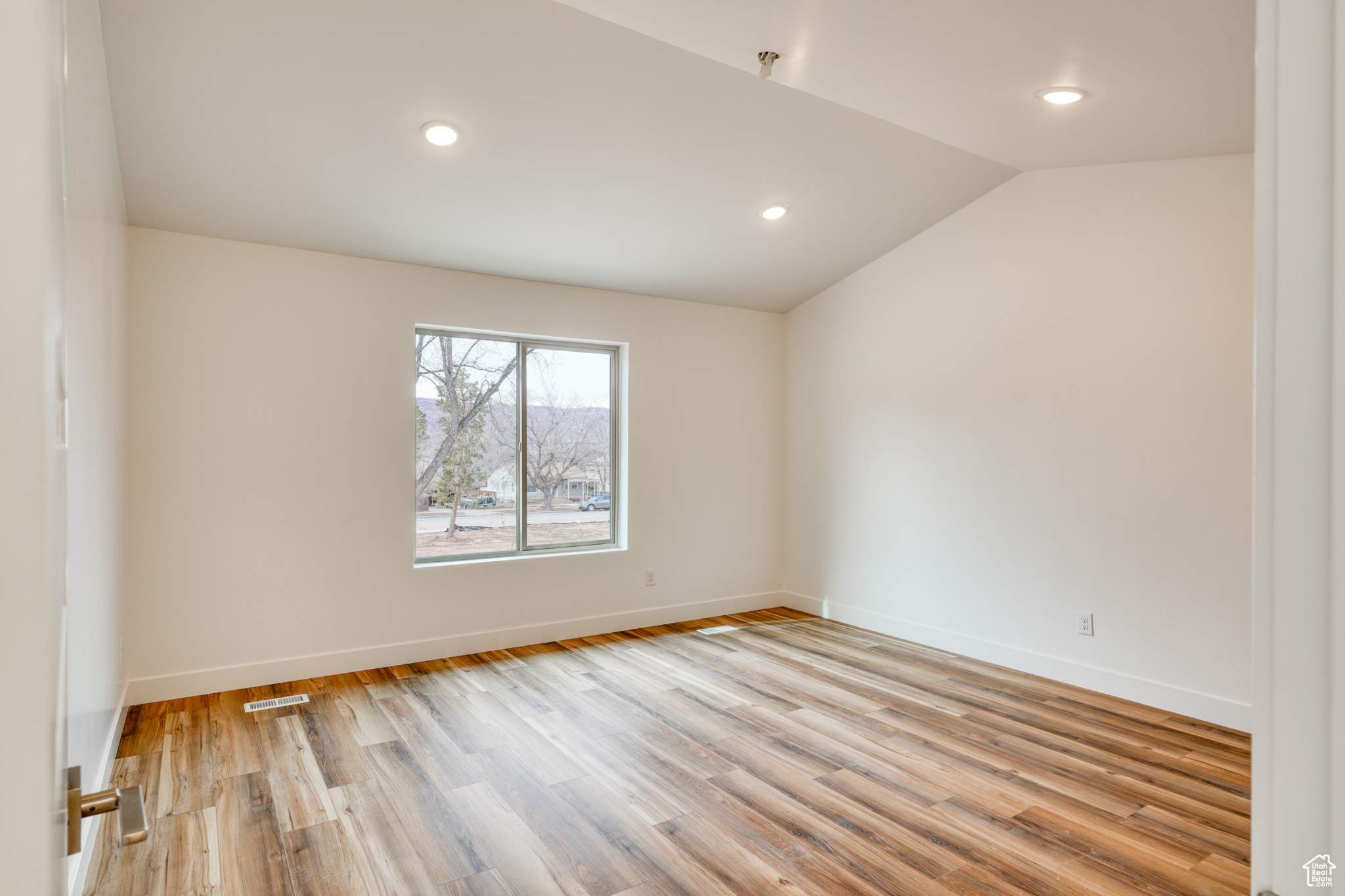 Unfurnished room featuring vaulted ceiling and light hardwood / wood-style floors