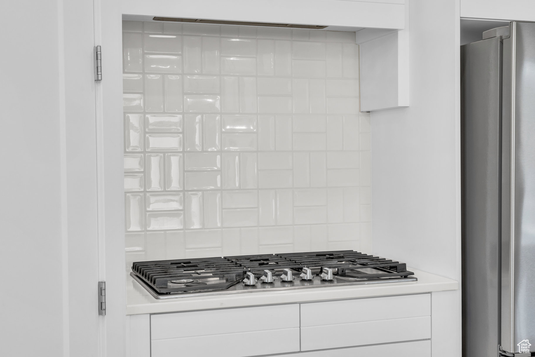 Details with white cabinetry, appliances with stainless steel finishes, and backsplash