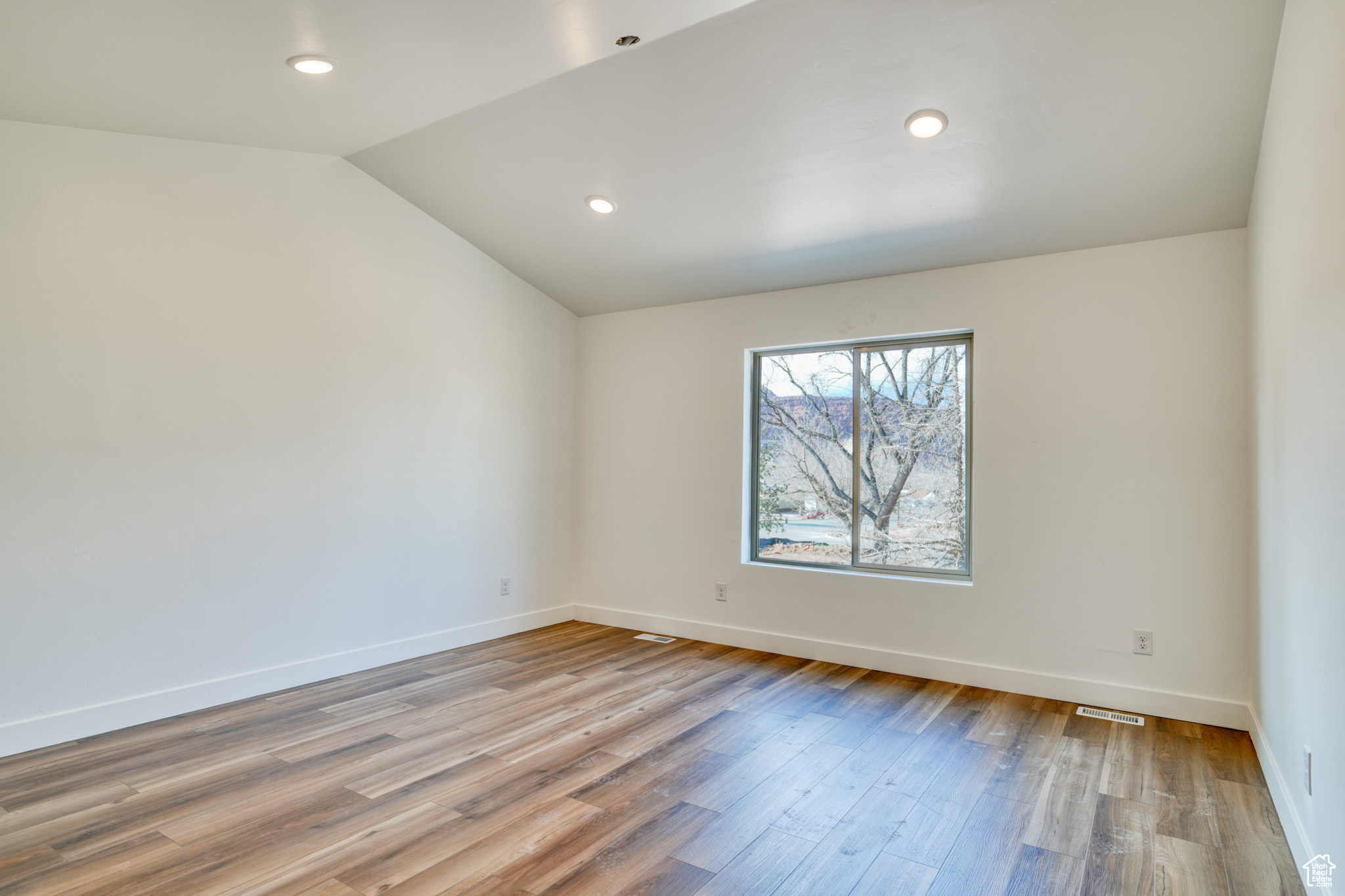 Empty room with lofted ceiling and light hardwood / wood-style floors