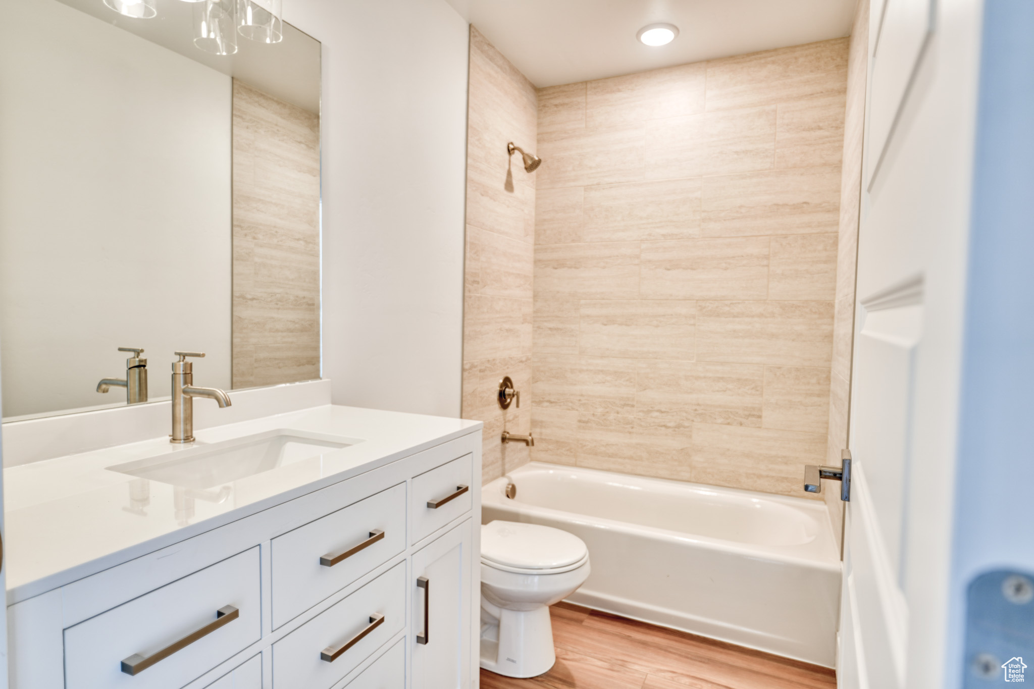 Full bathroom with wood-type flooring, tiled shower / bath, vanity, and toilet