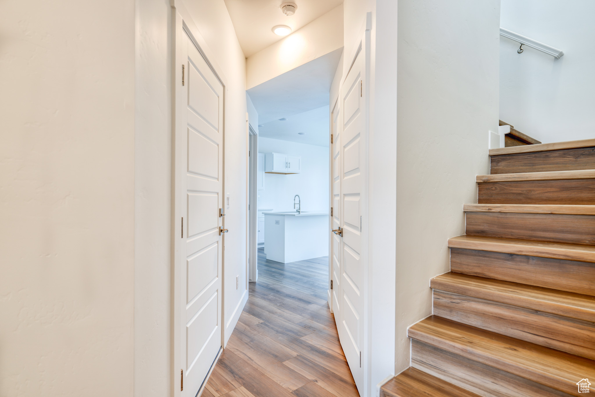 Staircase featuring sink and hardwood / wood-style floors
