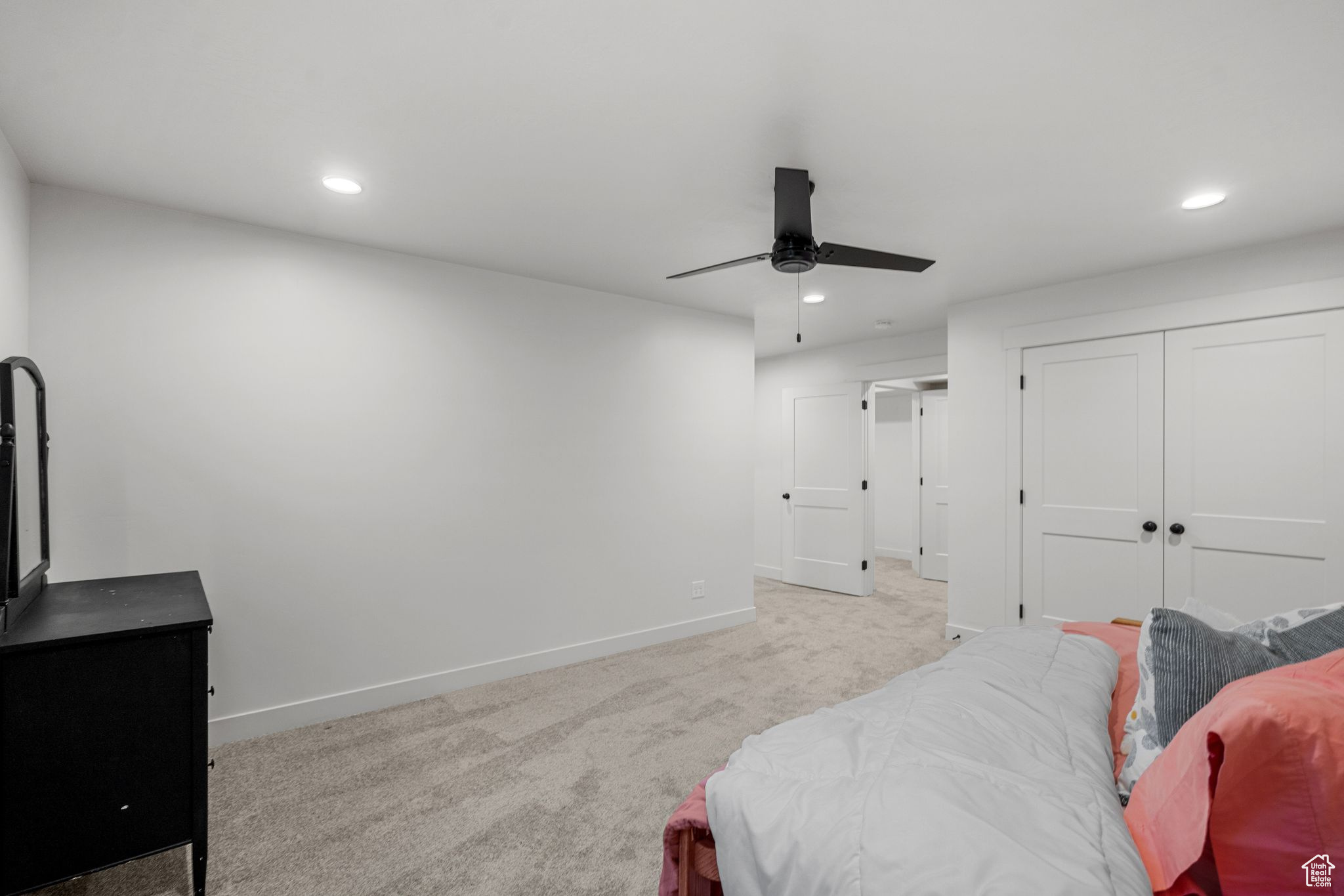 Carpeted bedroom with ceiling fan and a closet