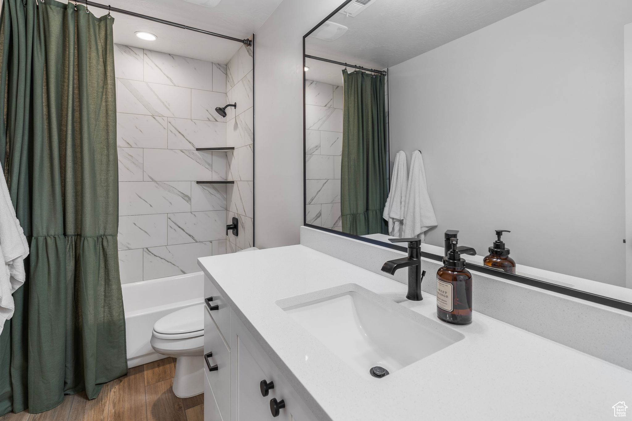 Full bathroom with hardwood / wood-style flooring, vanity, shower / bath combination with curtain, and toilet