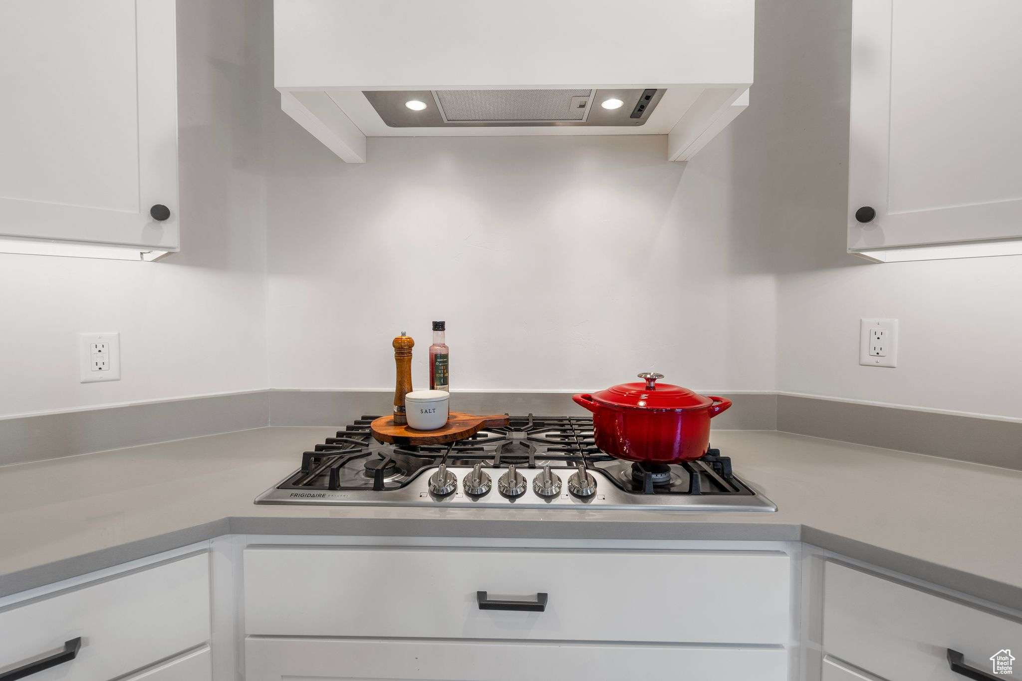 Kitchen featuring white cabinetry, stainless steel gas cooktop, and custom range hood