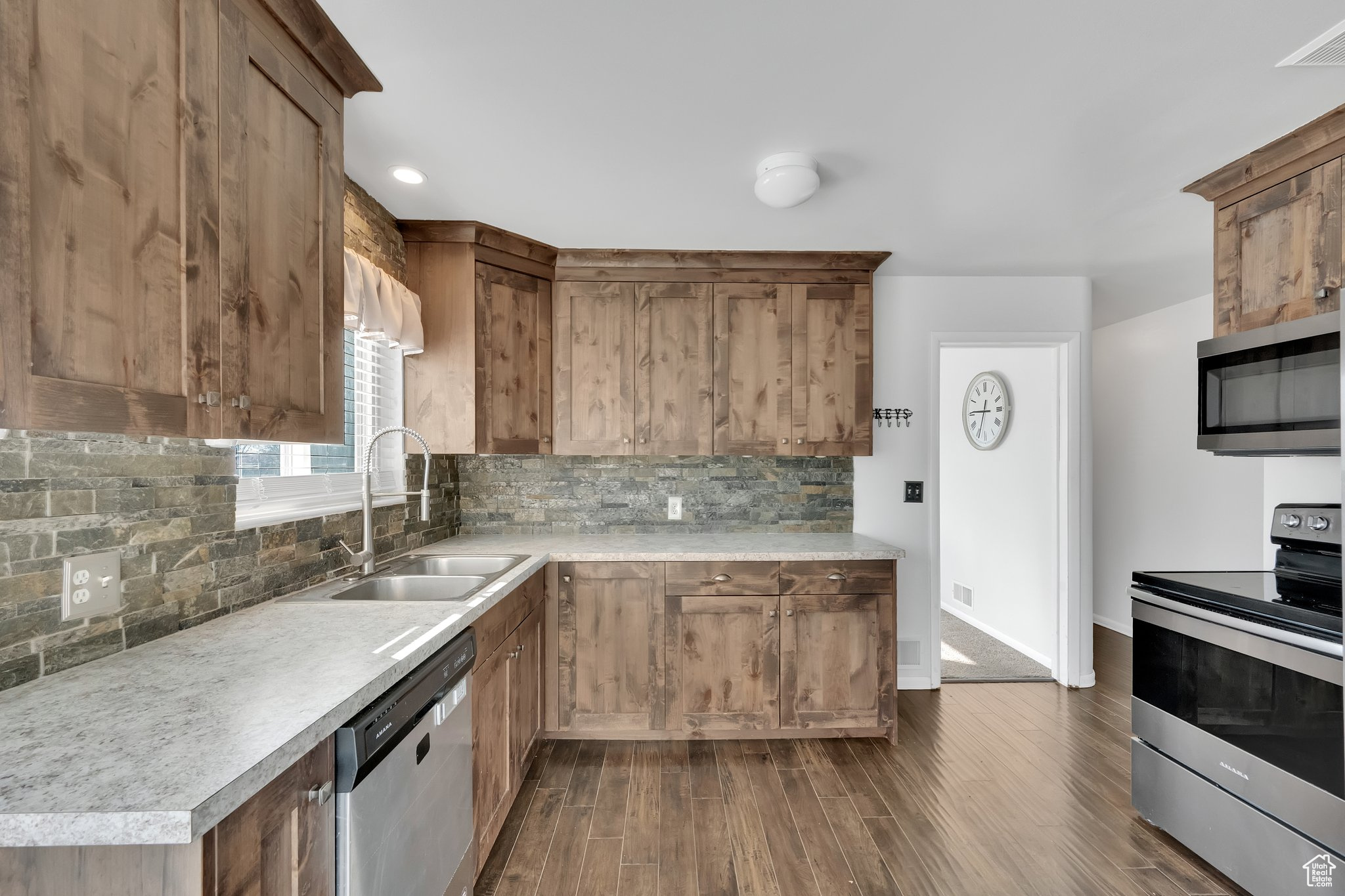 Kitchen featuring sink, decorative backsplash, dark wood-type flooring, and stainless steel appliances