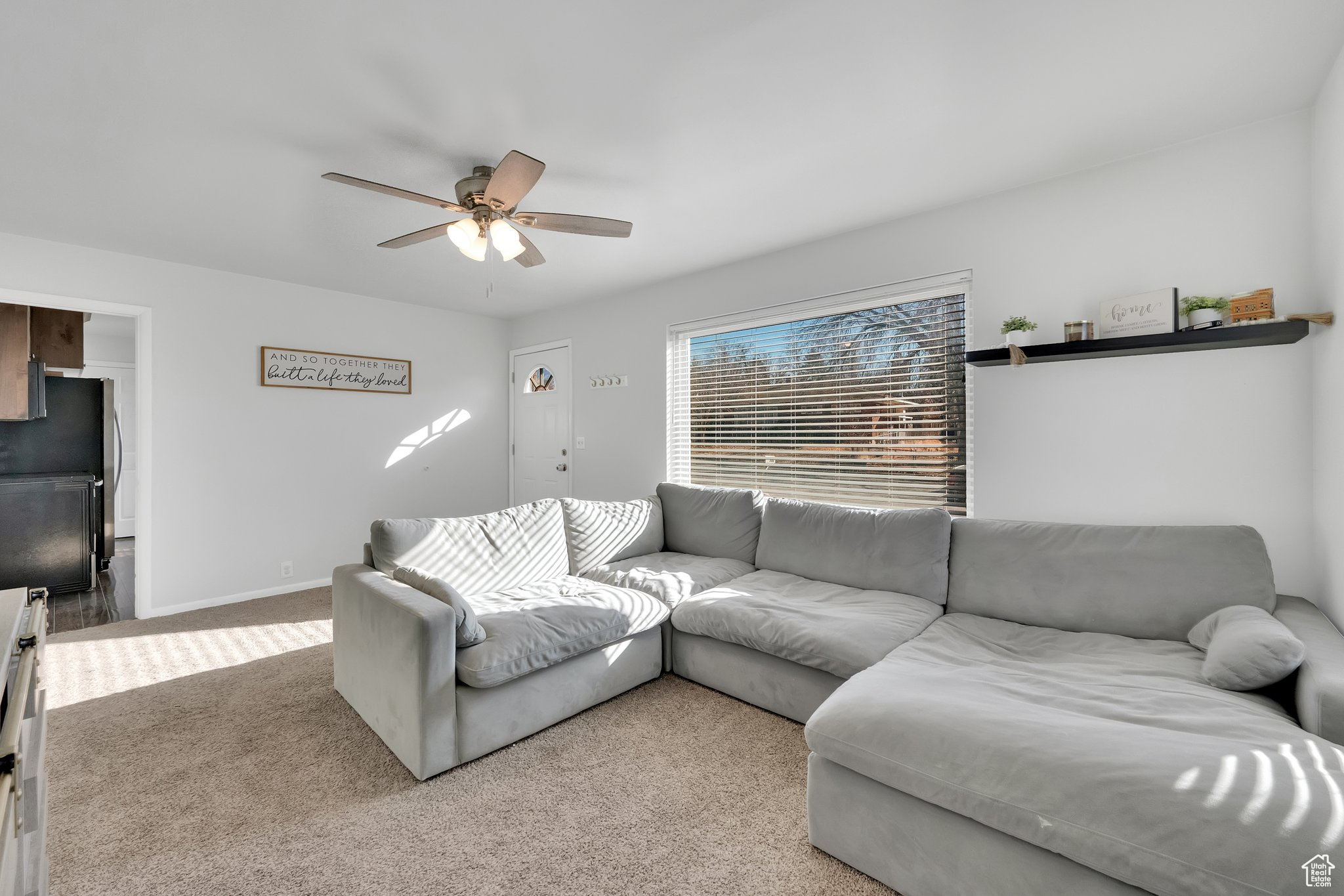 Carpeted living room featuring ceiling fan