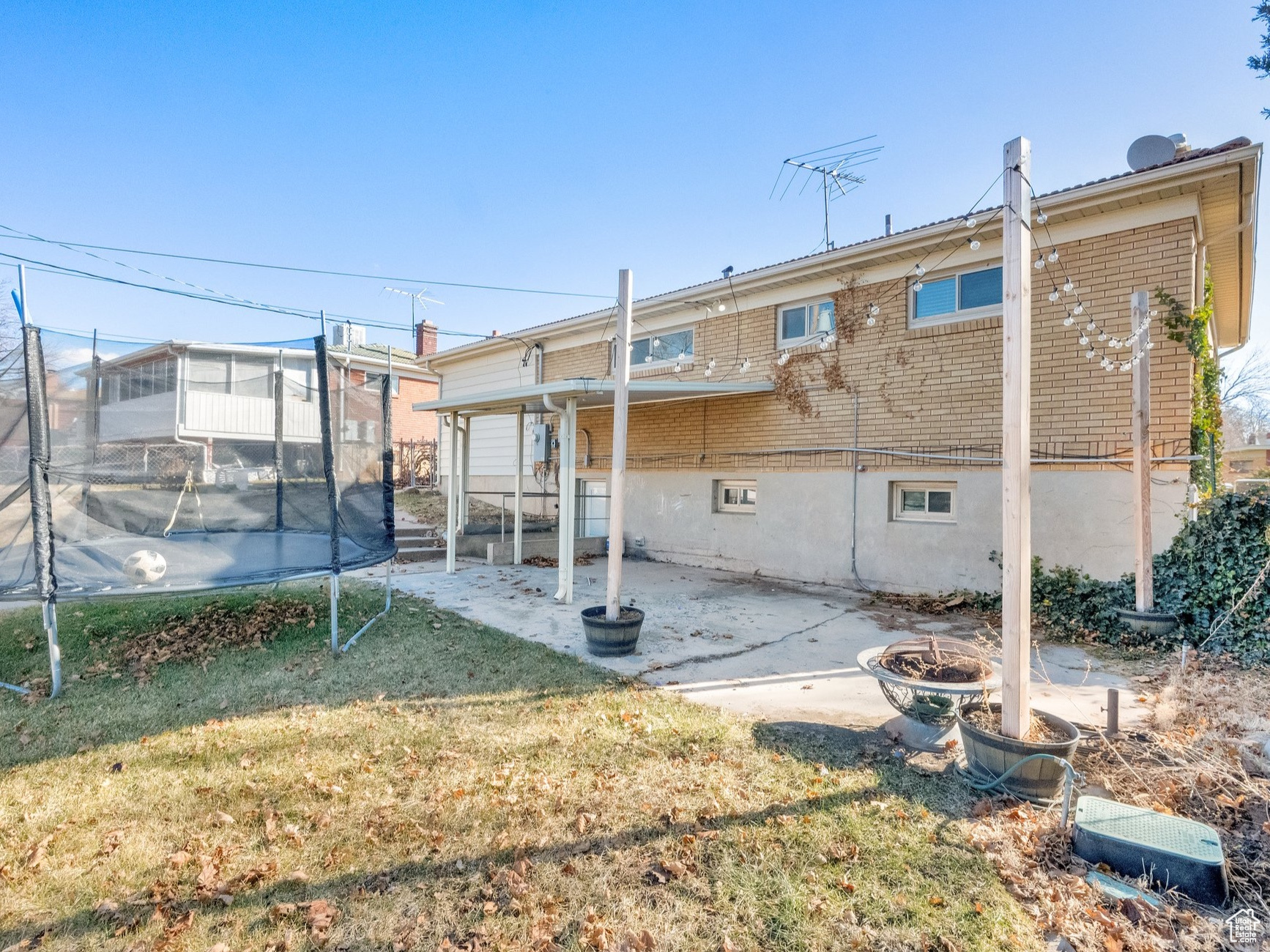 Rear view of property with an outdoor fire pit, a patio, a trampoline, and a lawn