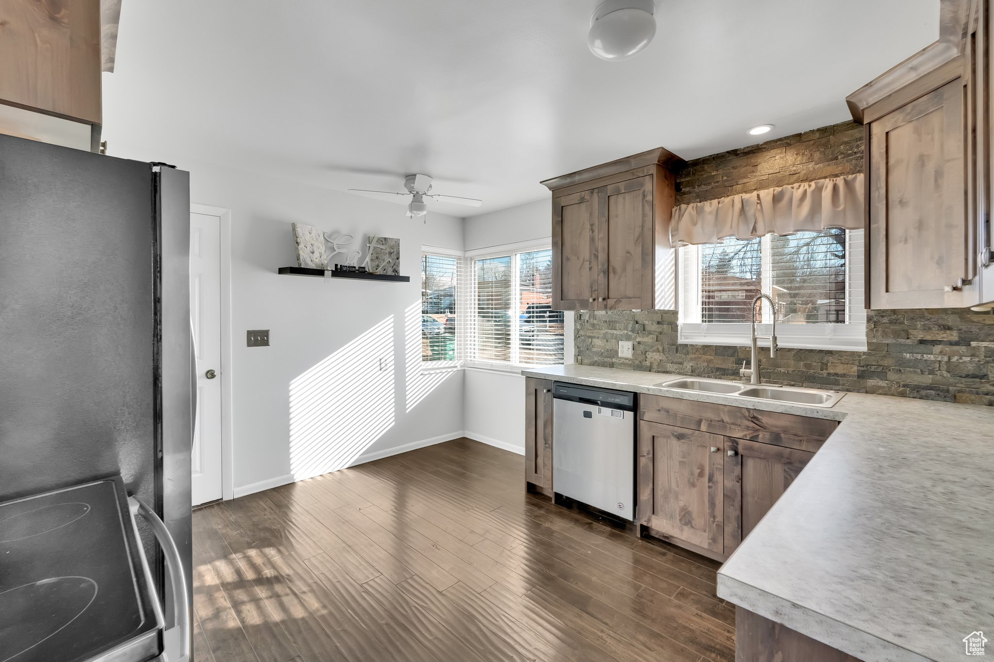 Kitchen with sink, ceiling fan, appliances with stainless steel finishes, backsplash, and dark hardwood / wood-style floors