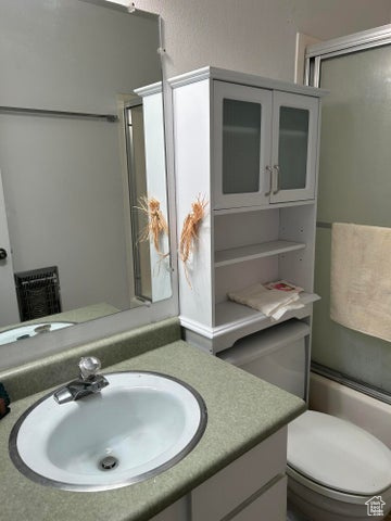 Full bathroom with vanity, toilet, and combined bath / shower with glass door