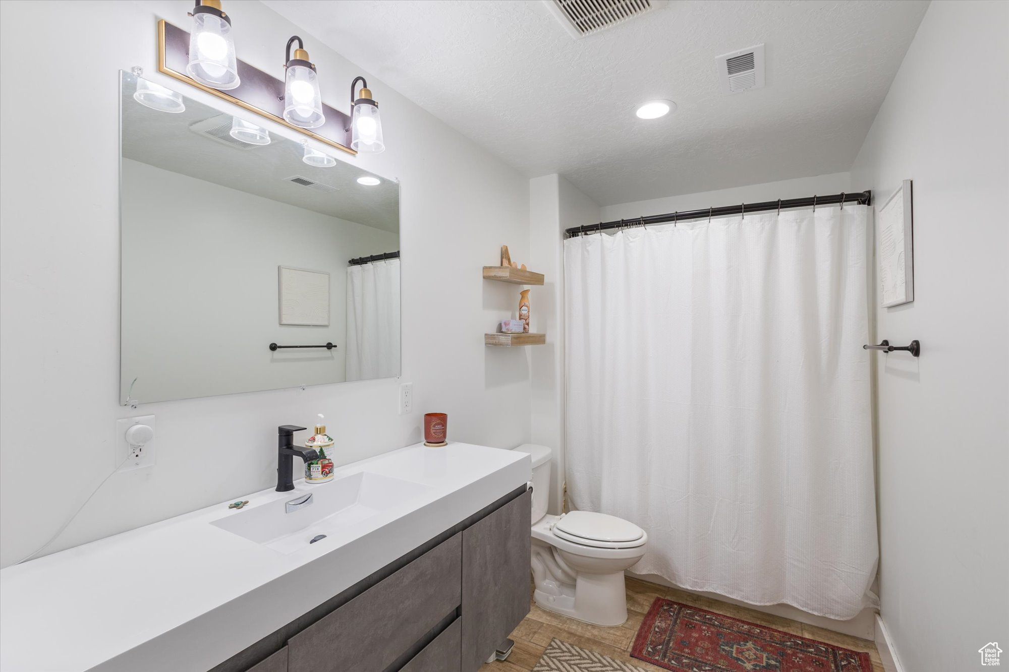 Bathroom with a shower with curtain, vanity, and toilet