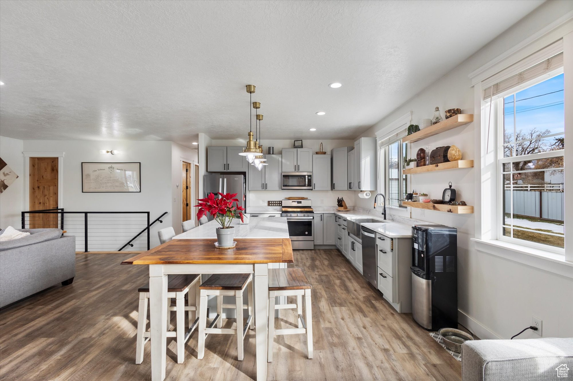 Kitchen featuring sink, gray cabinetry, decorative light fixtures, light wood-type flooring, and appliances with stainless steel finishes