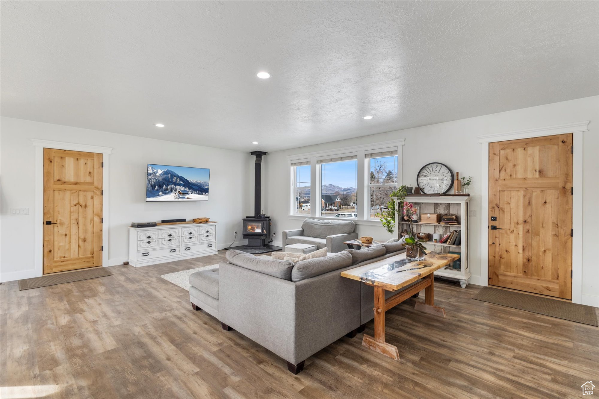 Living room with a wood stove, hardwood / wood-style floors, and a textured ceiling