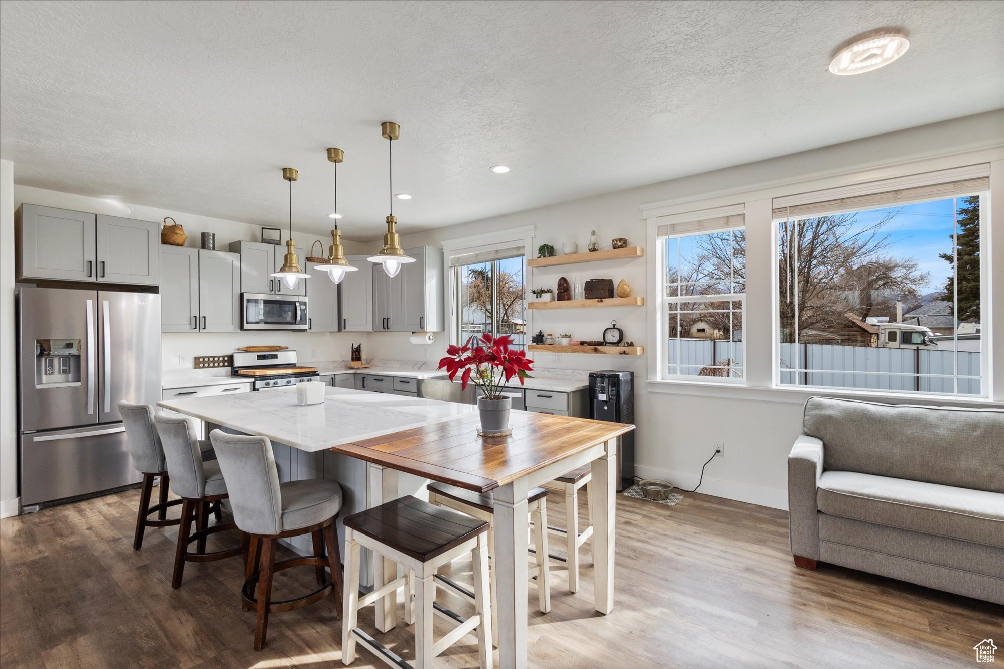 Kitchen featuring stainless steel appliances, wood-type flooring, pendant lighting, and gray cabinetry