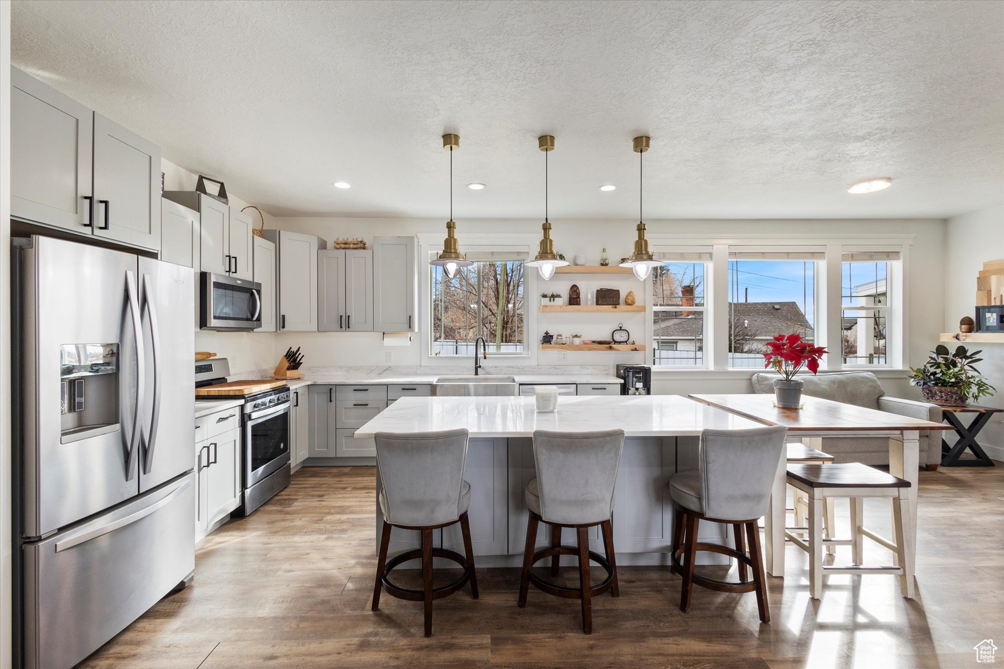 Kitchen with a kitchen bar, hanging light fixtures, a kitchen island, a wealth of natural light, and stainless steel appliances