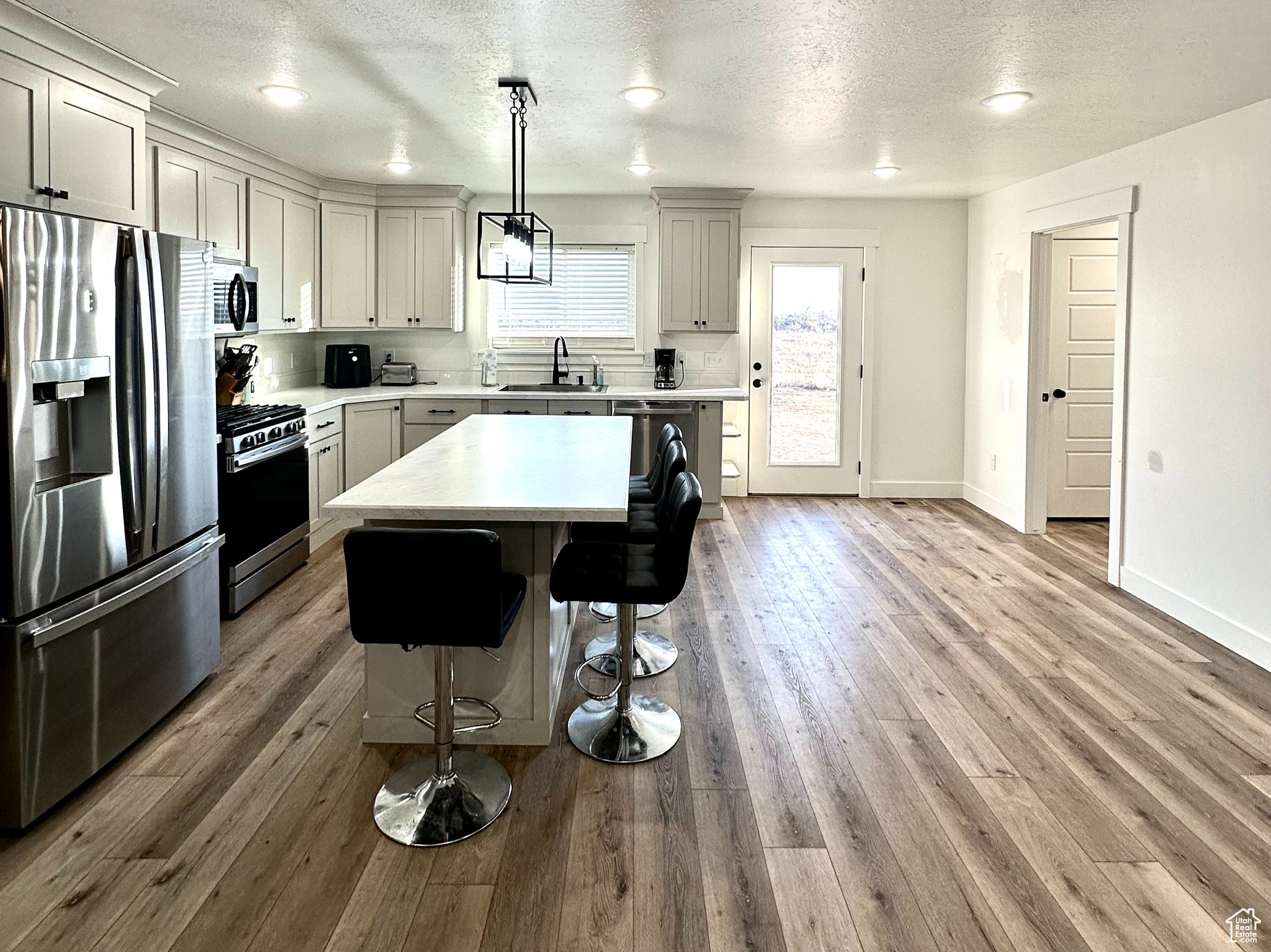 Kitchen with pendant lighting, a breakfast bar area, light hardwood / wood-style flooring, stainless steel appliances, and a center island
