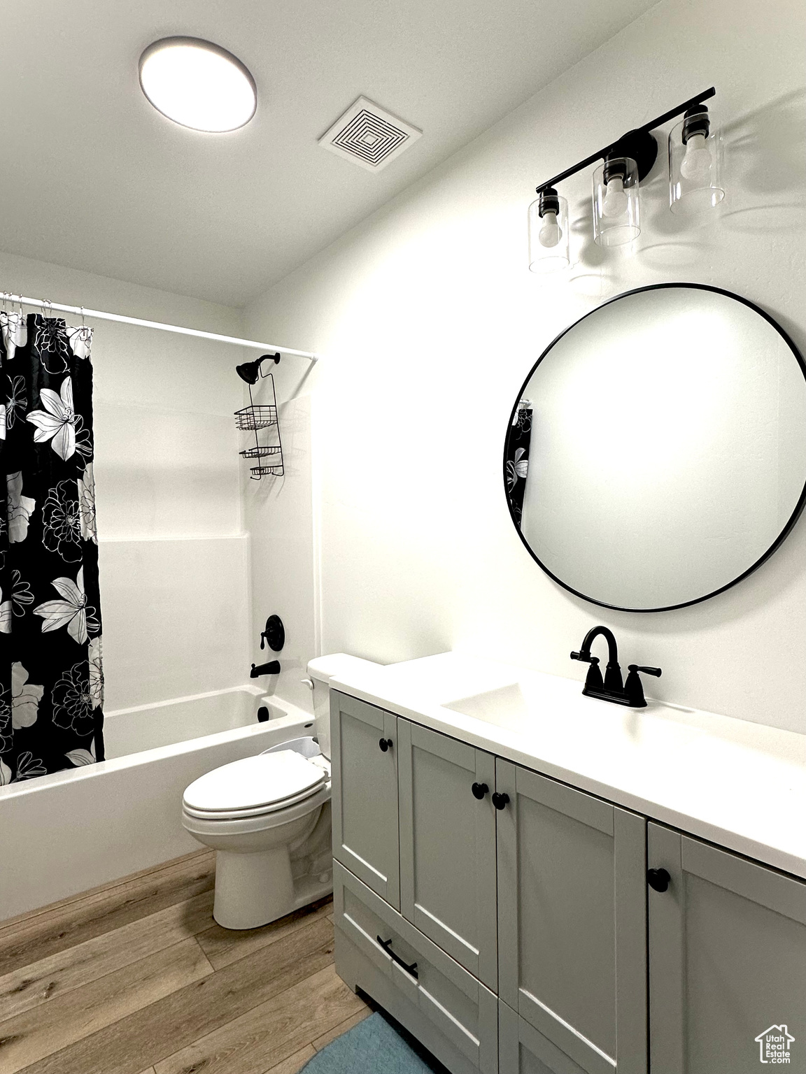 Full bathroom featuring vanity, hardwood / wood-style floors, shower / bath combination with curtain, and toilet