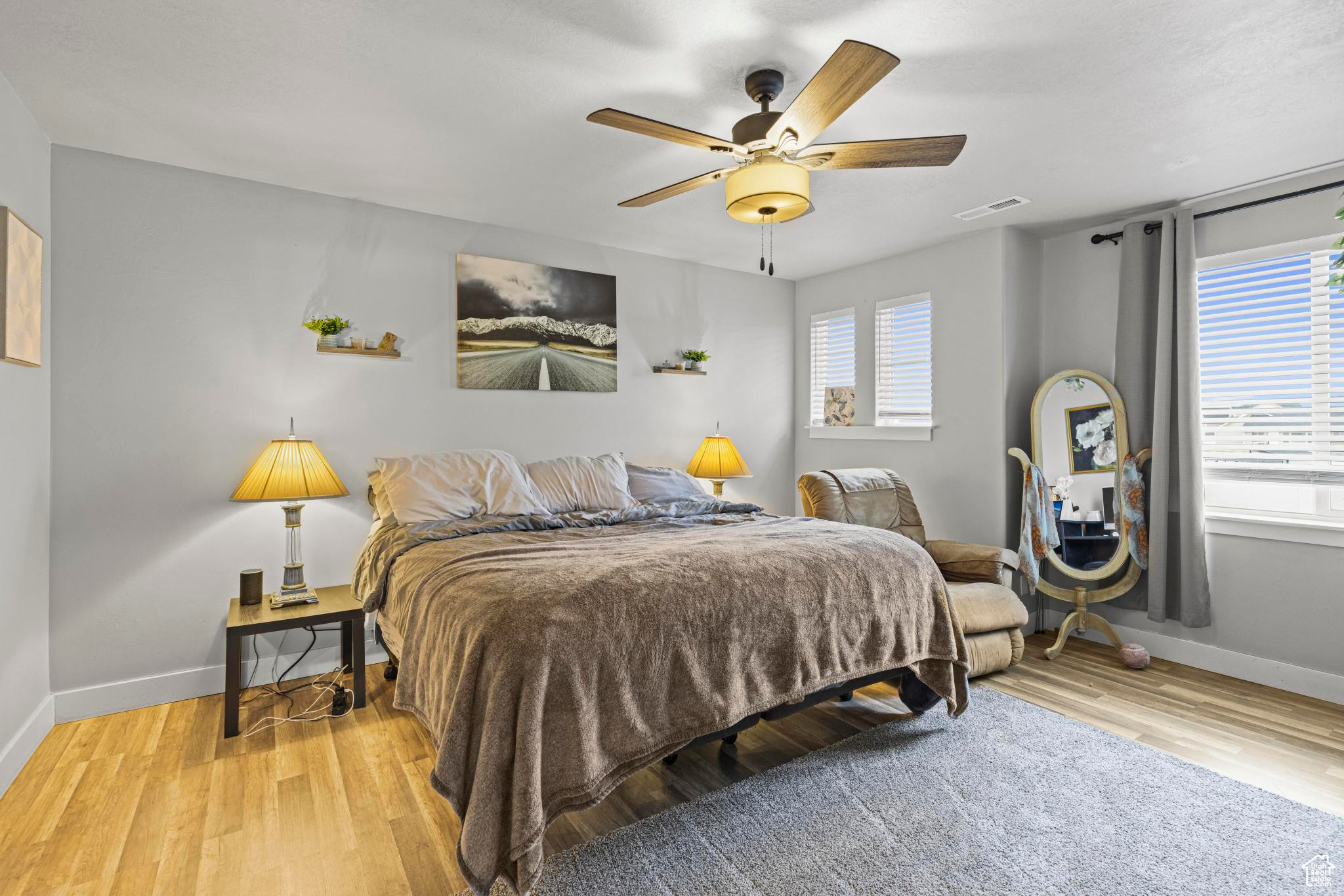 Bedroom featuring ceiling fan, multiple windows, and light wood-type flooring