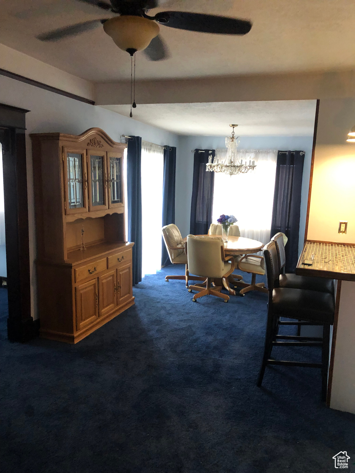 Carpeted dining area featuring ceiling fan with notable chandelier