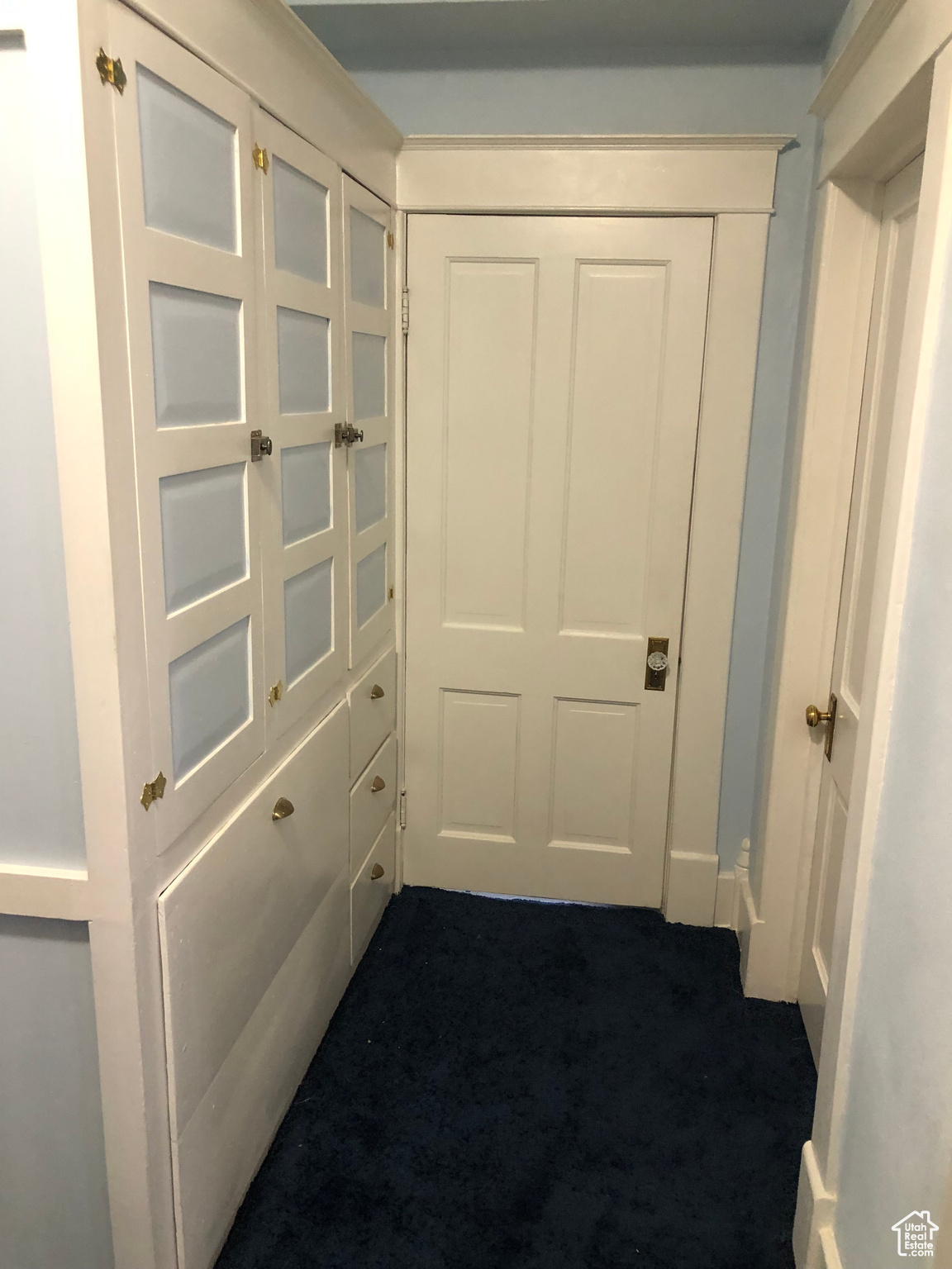 Hallway featuring dark colored carpet