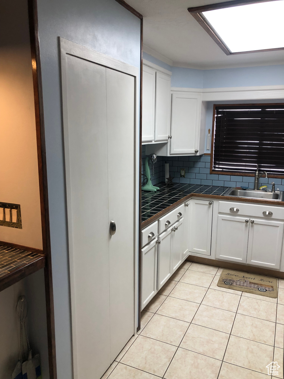 Kitchen with white cabinetry, sink, decorative backsplash, and light tile patterned floors