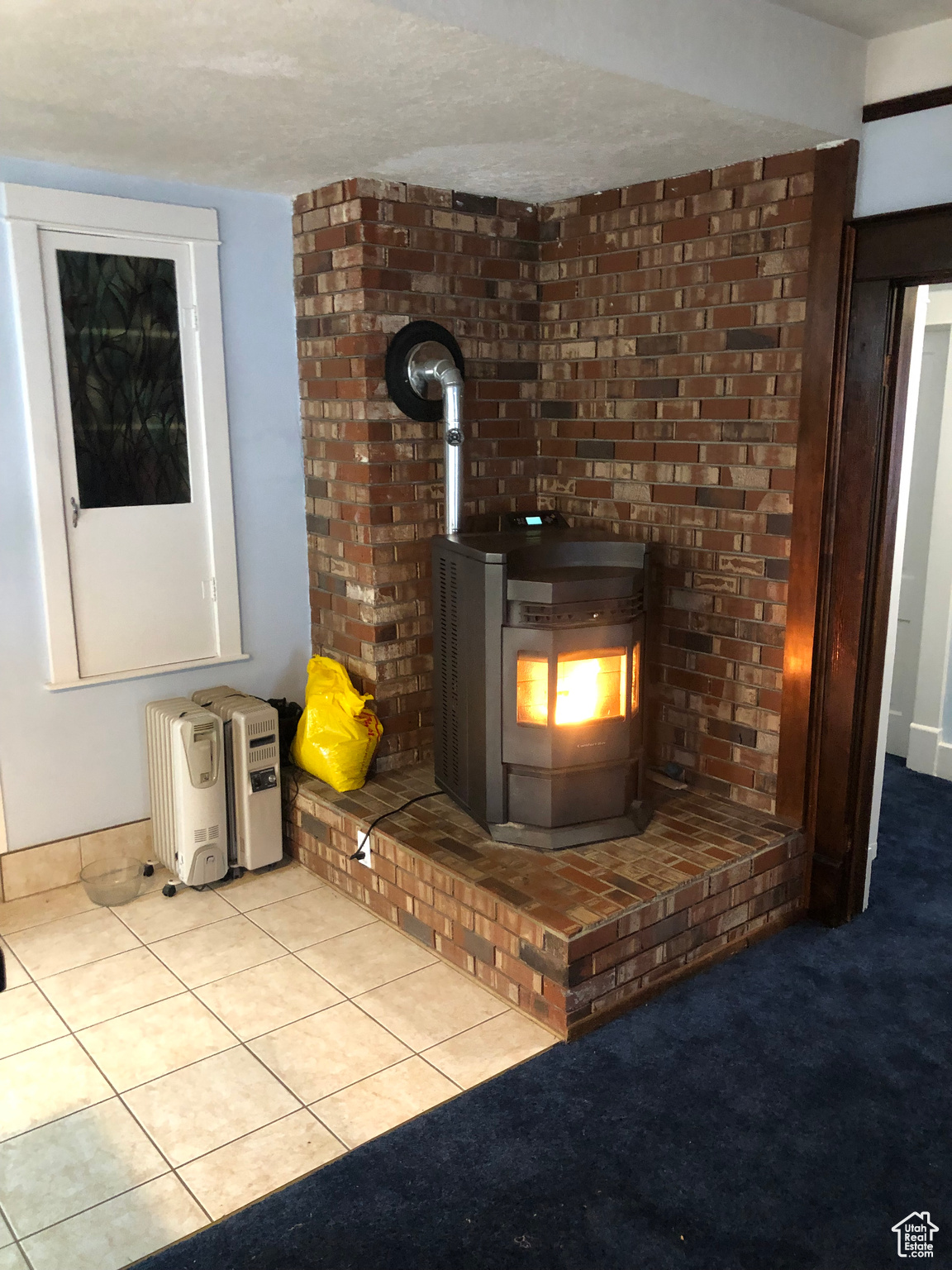 Interior details with carpet, a wood stove, and a textured ceiling