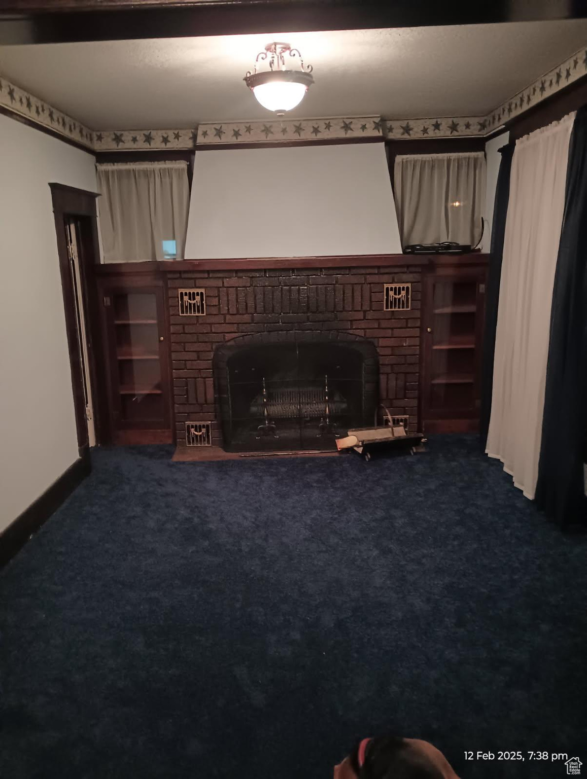Unfurnished living room with a brick fireplace and carpet