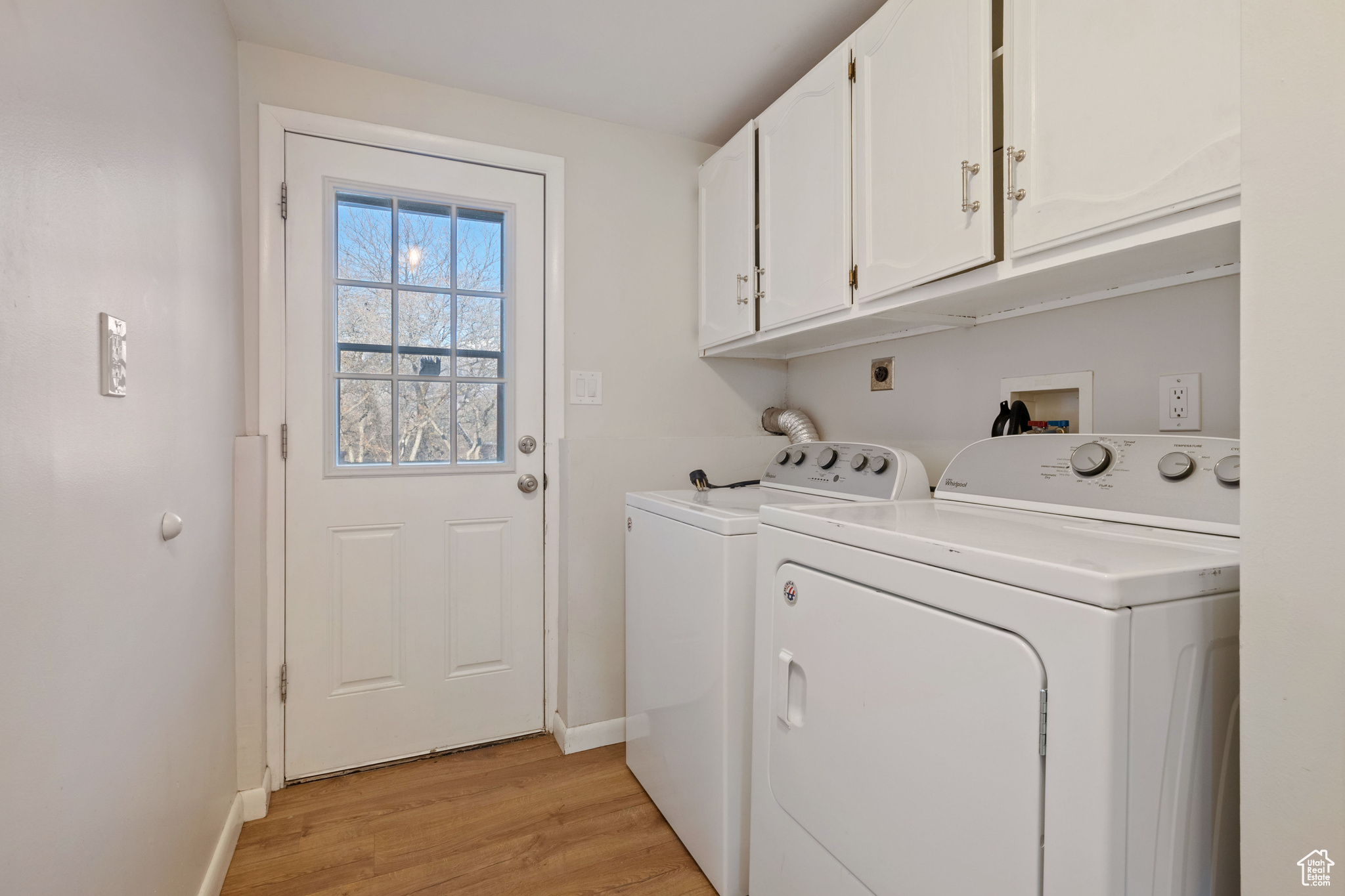 Laundry area featuring cabinets, washer and clothes dryer, and light wood-type flooring
