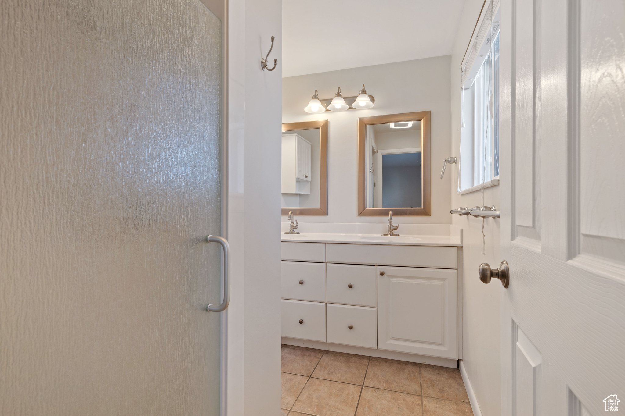 Bathroom featuring tile patterned flooring, vanity, and walk in shower