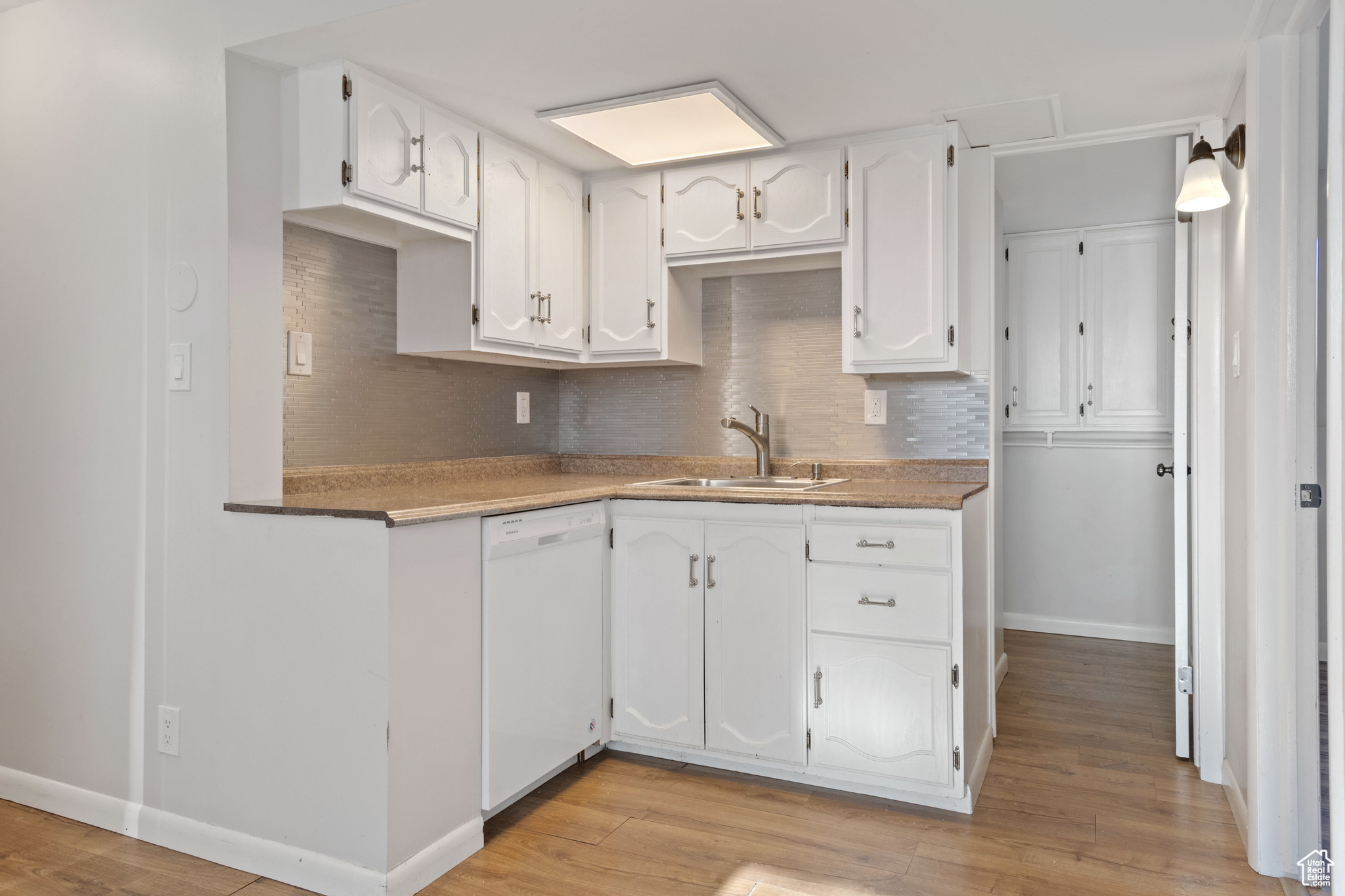 Kitchen with sink, white cabinets, and white dishwasher