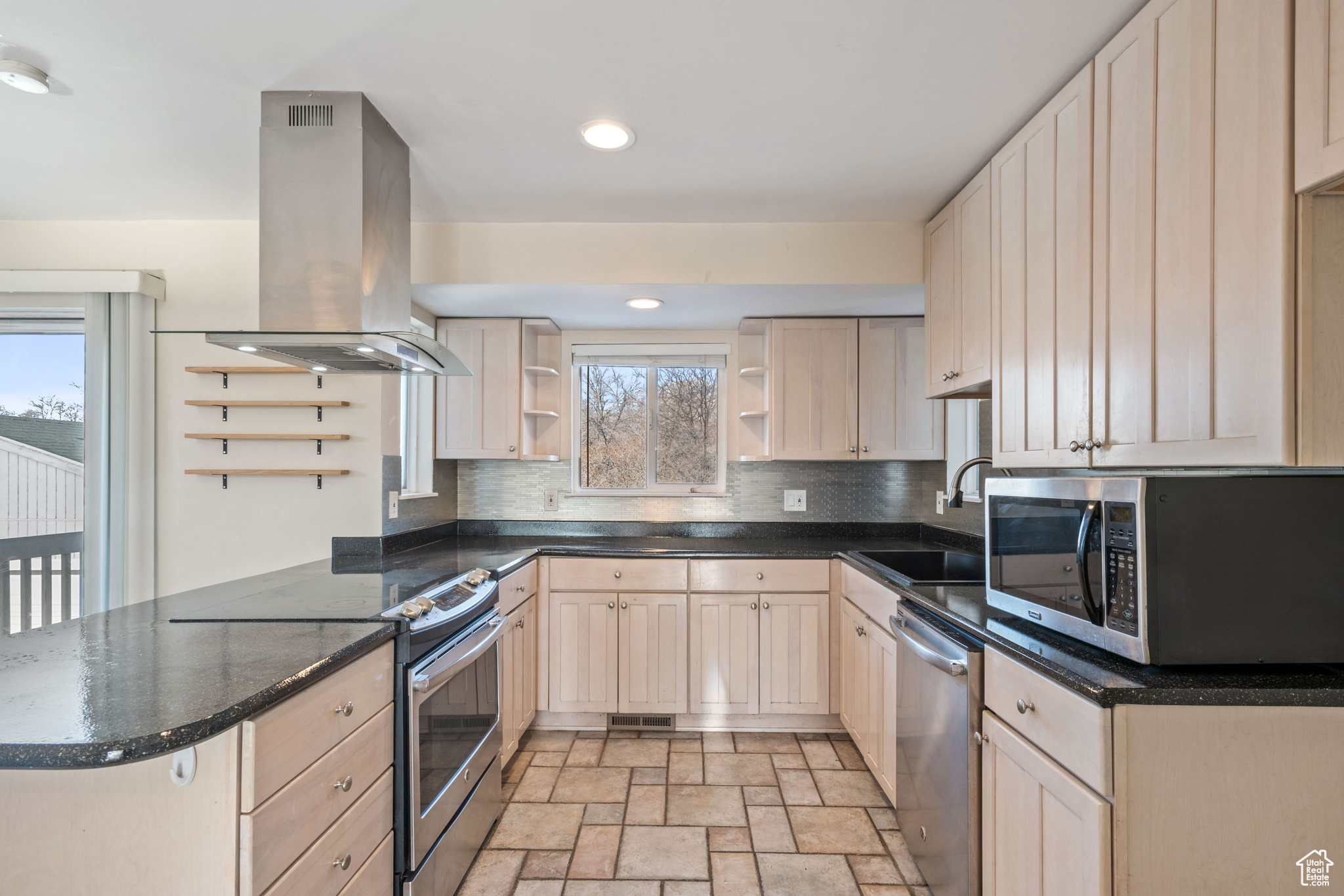 Kitchen with sink, appliances with stainless steel finishes, island exhaust hood, decorative backsplash, and kitchen peninsula