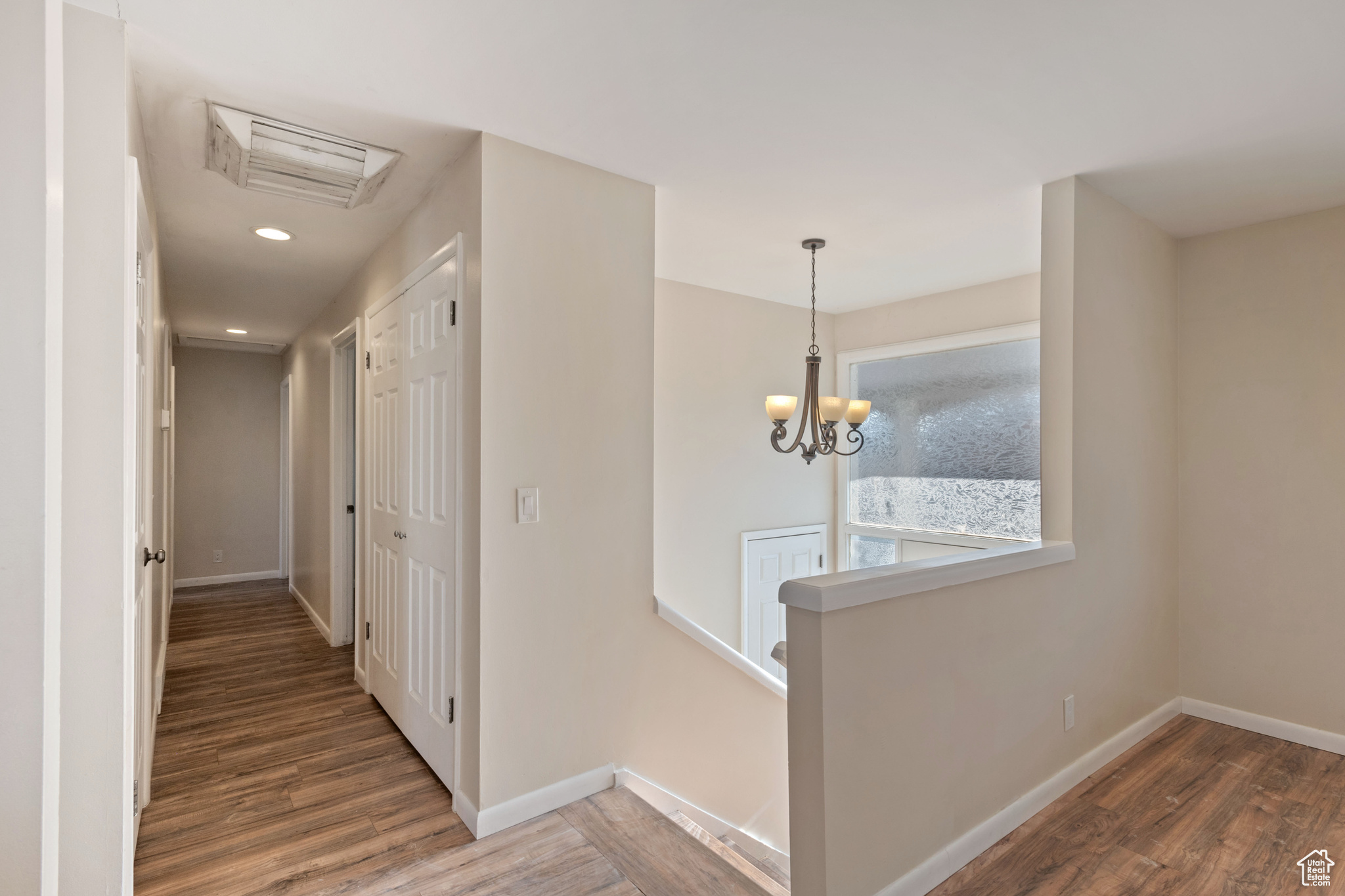 Hallway with a notable chandelier and dark hardwood / wood-style floors