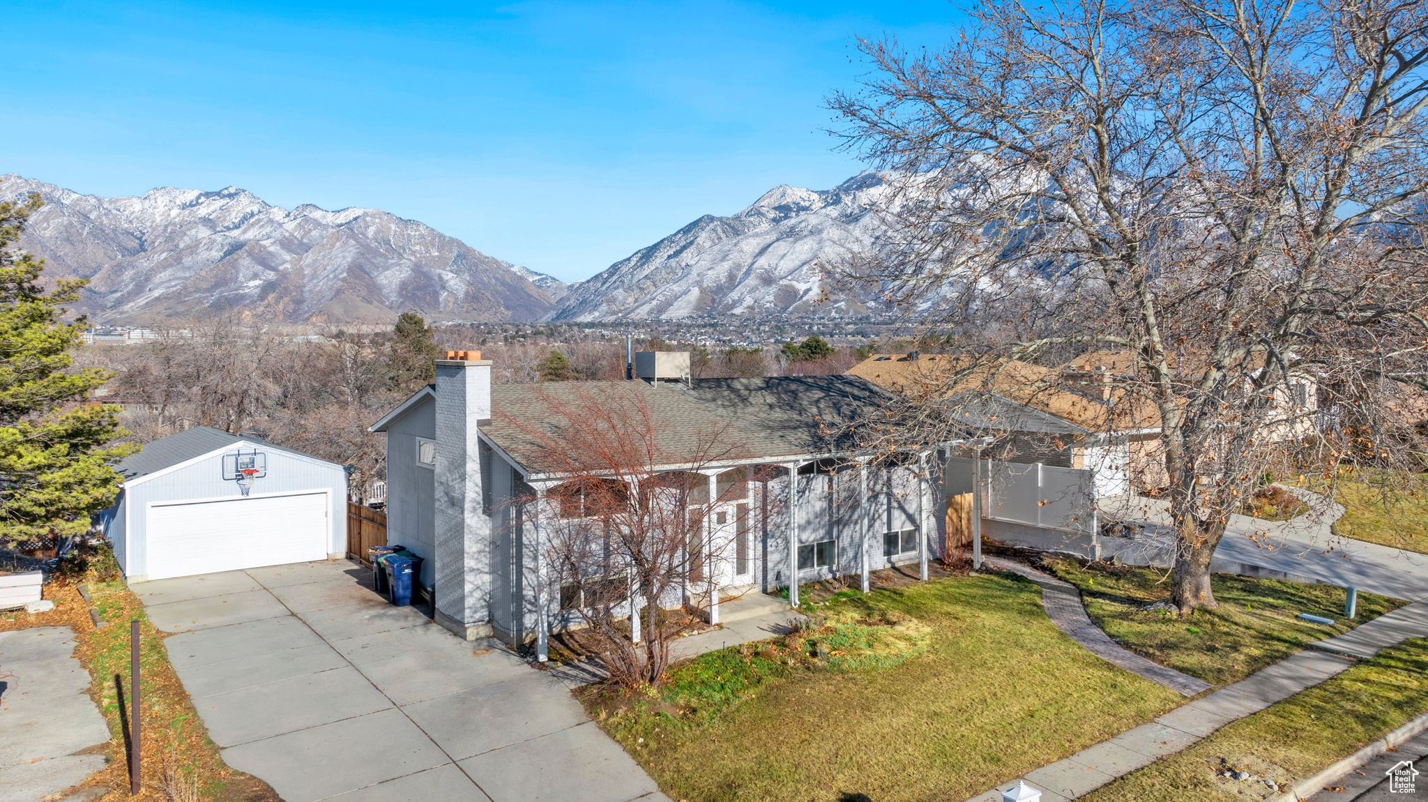 View of front of home featuring a mountain view, a garage, an outdoor structure, and a front lawn