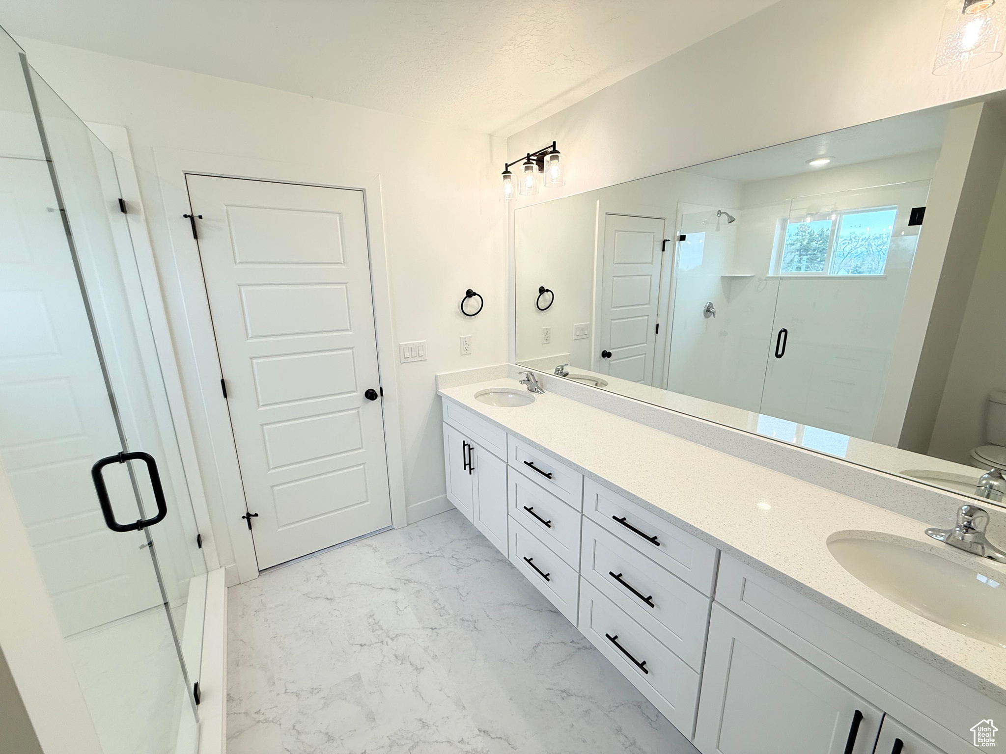 Bathroom with marble finish floor, a sink, a shower stall, and double vanity