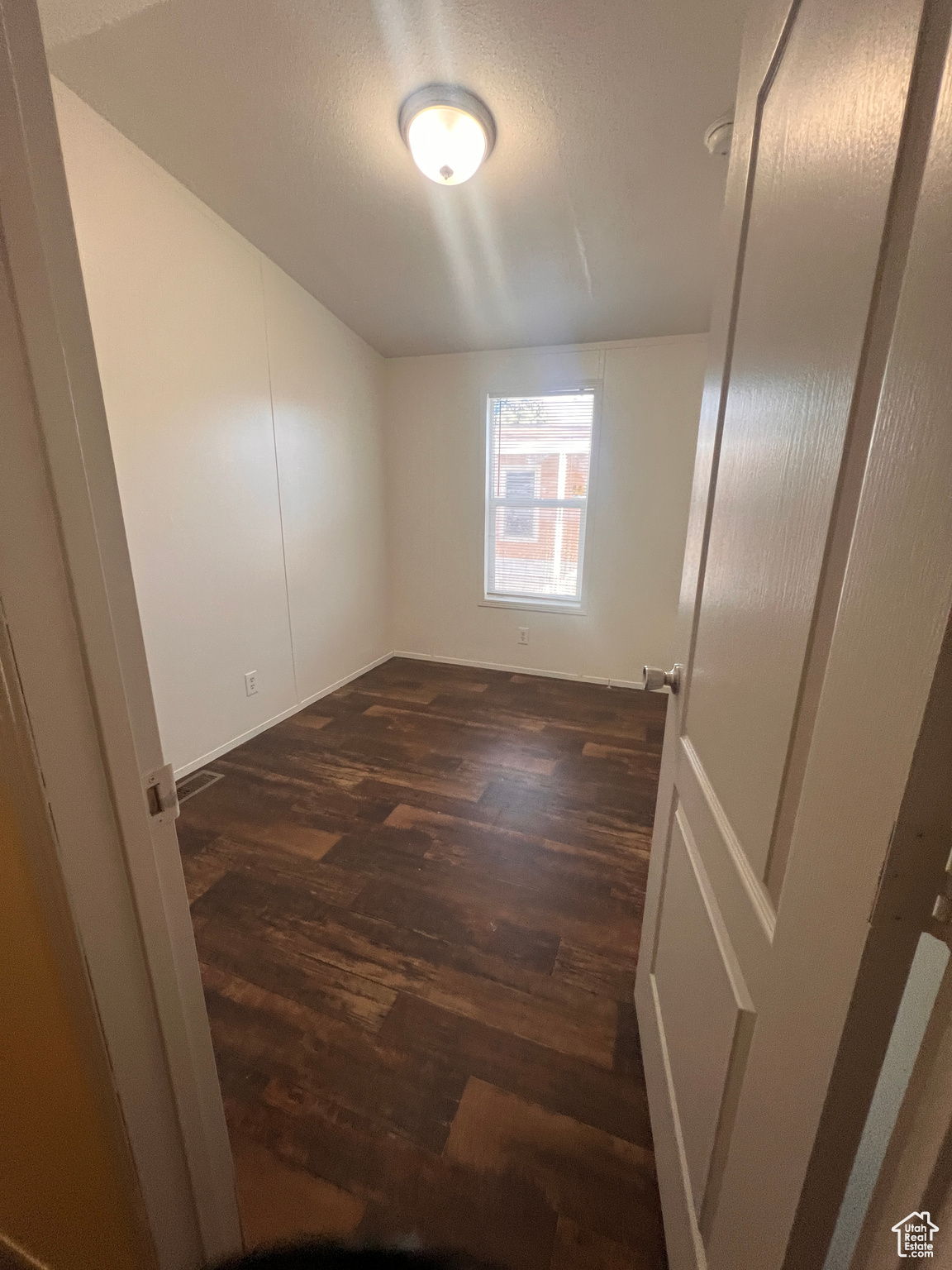 Empty room with dark wood-style floors and a textured ceiling
