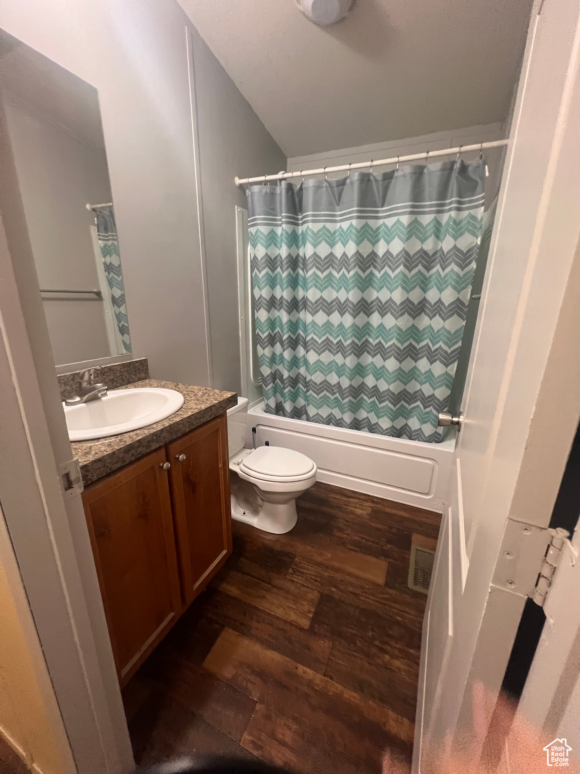 Bathroom featuring visible vents, shower / bath combo with shower curtain, toilet, wood finished floors, and vanity