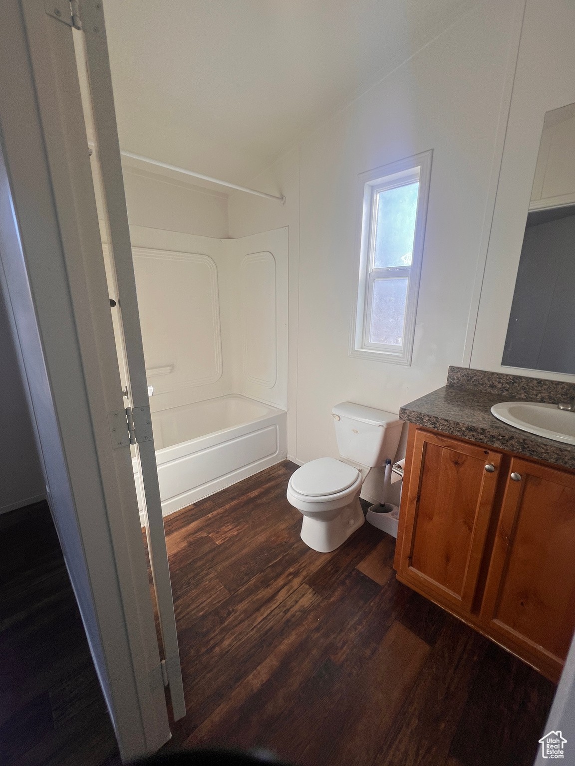 Bathroom with shower / bath combination, toilet, wood finished floors, and vanity
