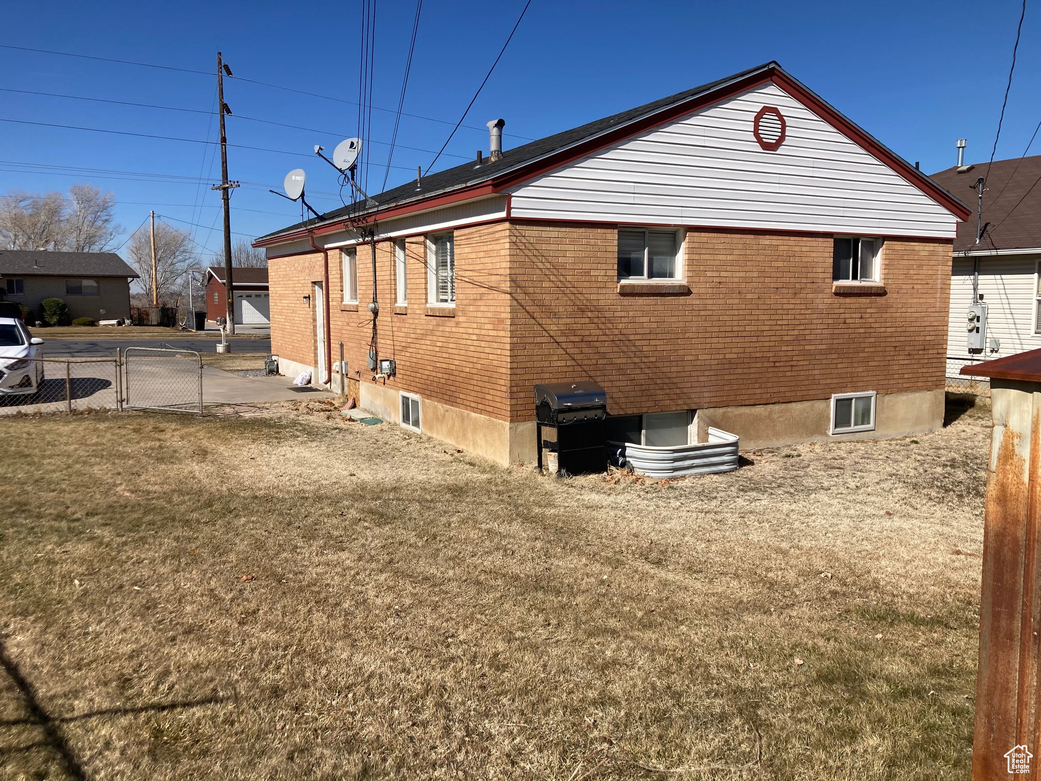 View of side of home featuring a yard, brick siding, and fence