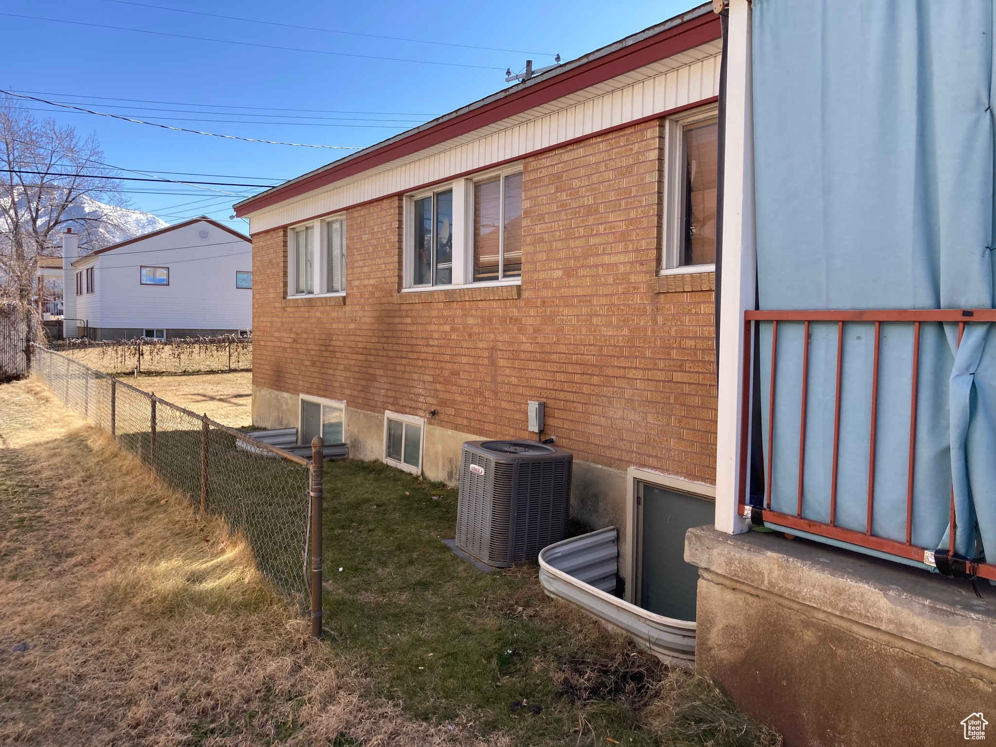 View of property exterior featuring central AC unit, a lawn, fence, and brick siding