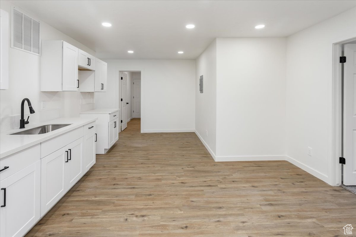 Kitchen featuring sink, light hardwood / wood-style flooring, and white cabinets