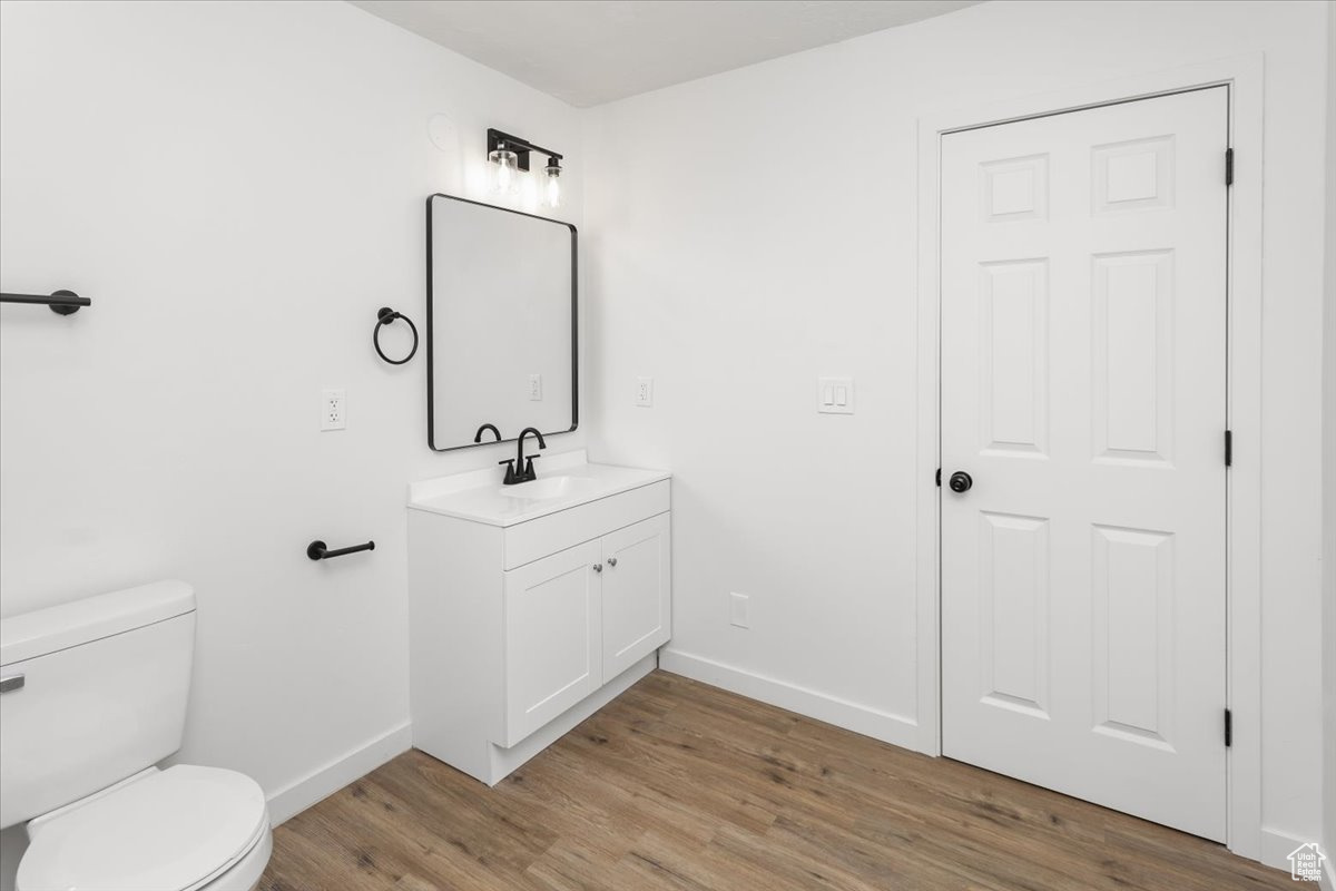 Bathroom with wood-type flooring, toilet, and vanity