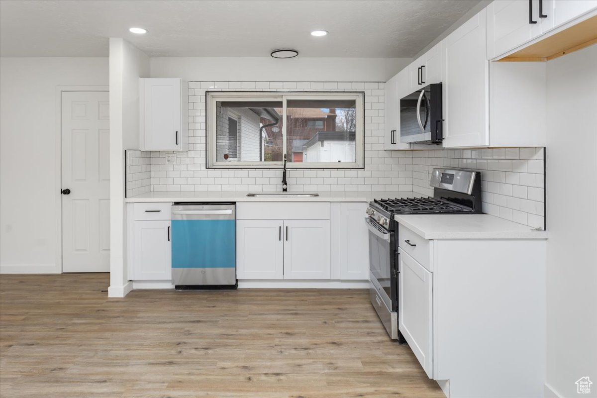 Kitchen featuring light wood-type flooring, stainless steel appliances, sink, and white cabinets