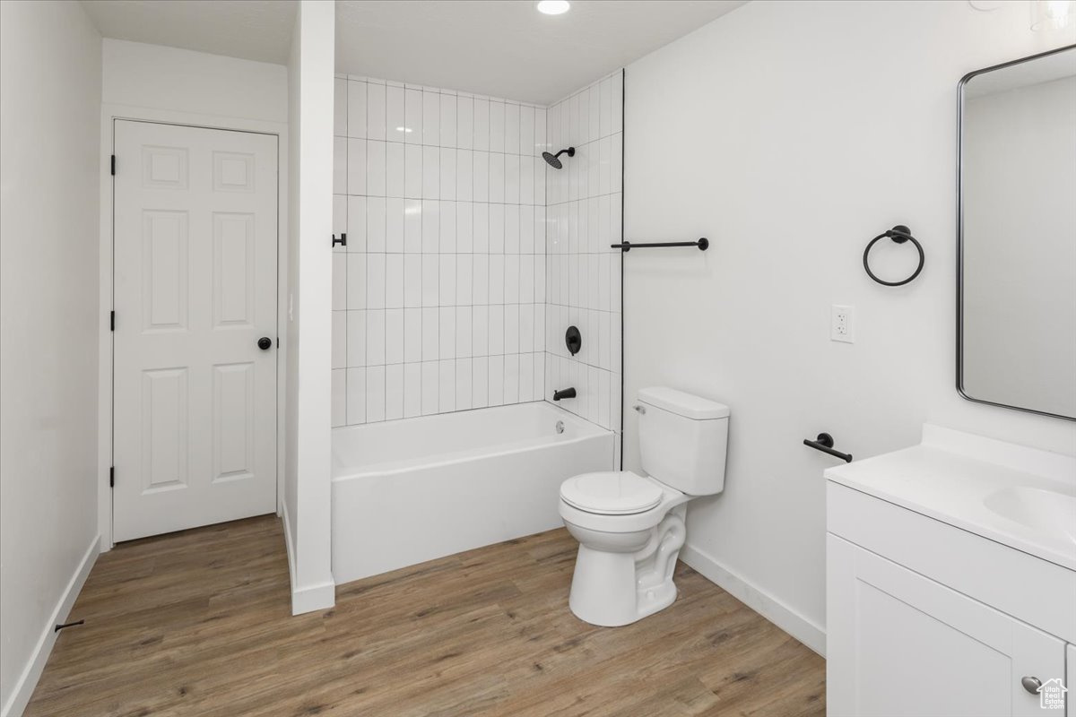 Full bathroom with vanity, wood-type flooring, tiled shower / bath, and toilet