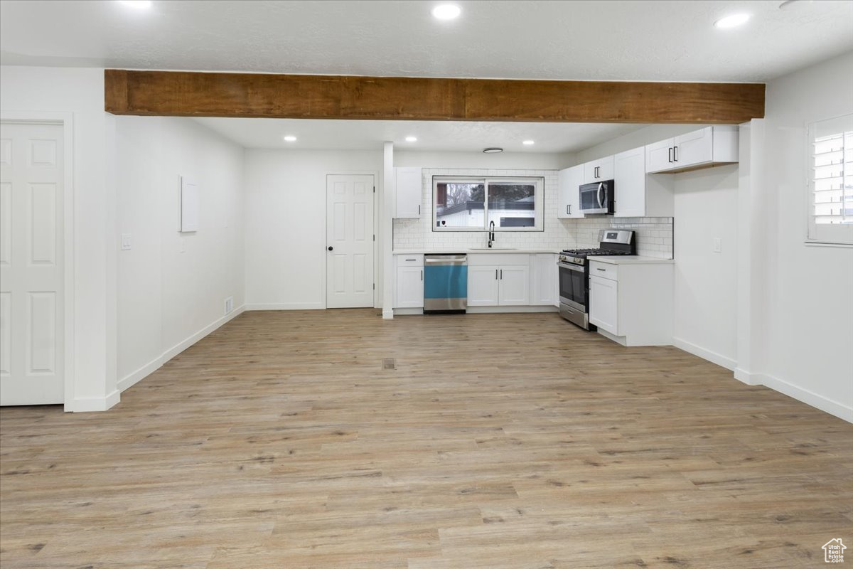 Kitchen featuring beamed ceiling, tasteful backsplash, appliances with stainless steel finishes, and white cabinets