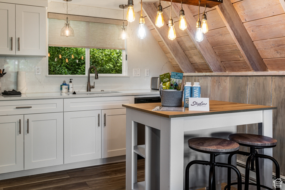Kitchen featuring white cabinetry, sink, hanging light fixtures, and wooden counters