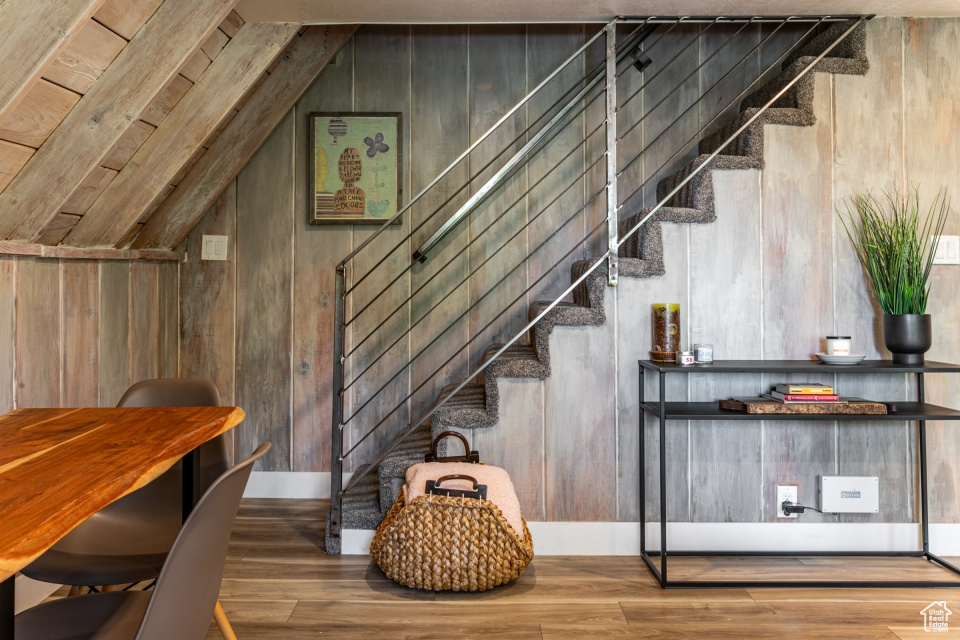 Staircase featuring lofted ceiling, hardwood / wood-style floors, and wooden walls