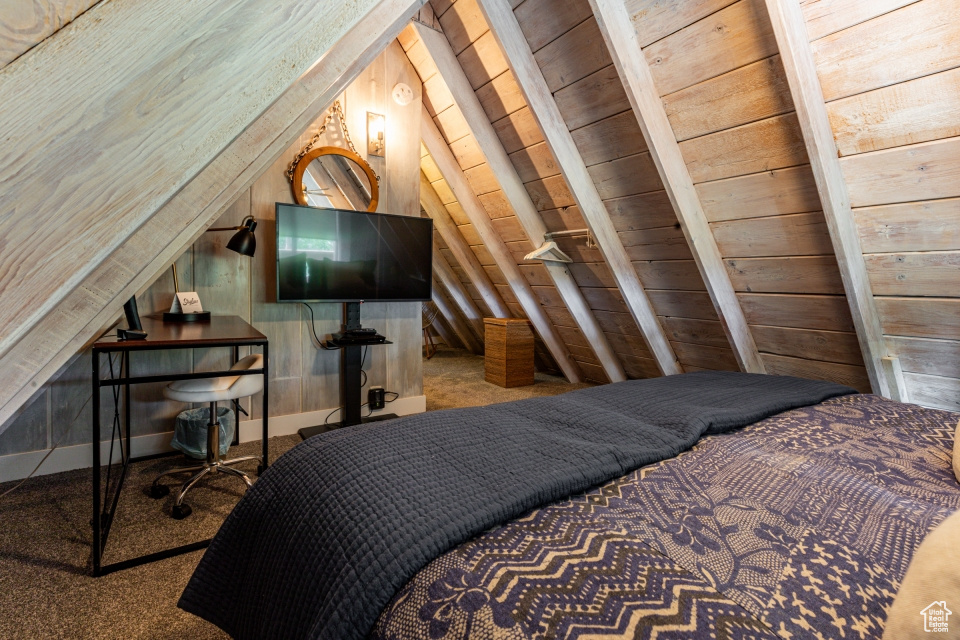 Bedroom with lofted ceiling, wooden walls, wooden ceiling, and carpet