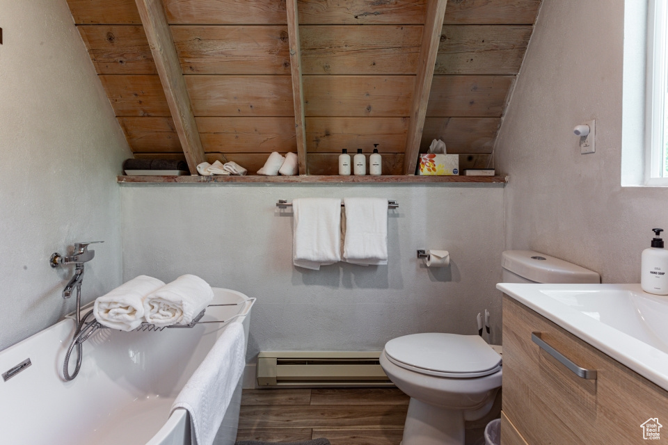Bathroom featuring hardwood / wood-style flooring, baseboard heating, vanity, a tub, and toilet