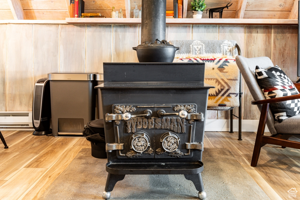 Interior details with a baseboard heating unit, hardwood / wood-style flooring, a wood stove, and wood walls